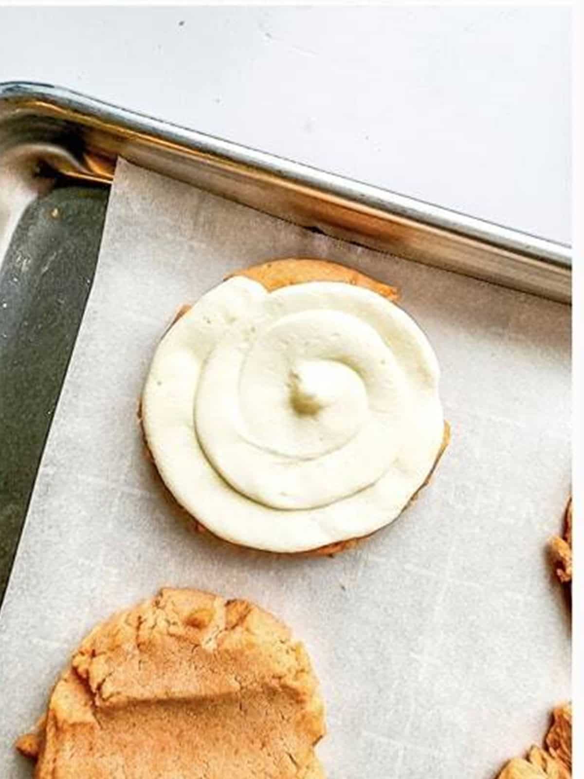Cream cheese frosting piped onto a strawberry shortcake cookie.