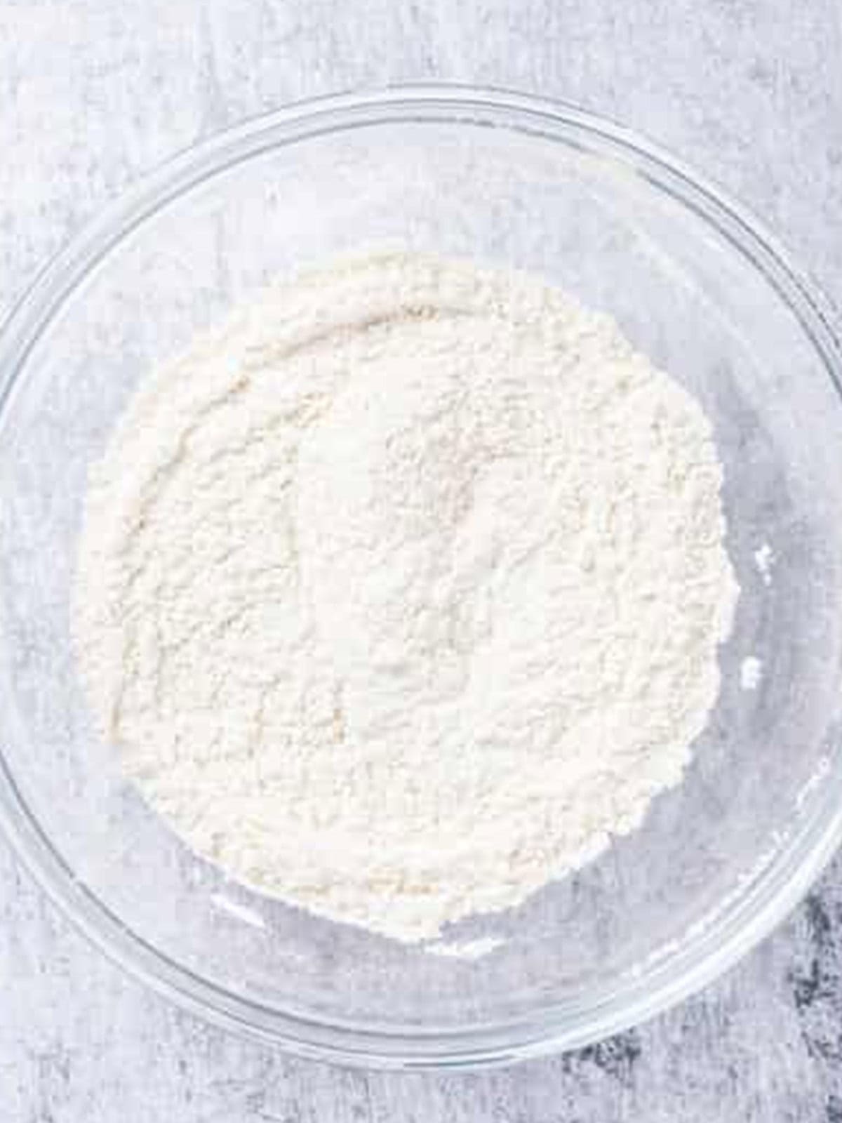 Flour, sugar, baking powder, baking soda, and salt sifted together in a bowl for shortcake biscuits.