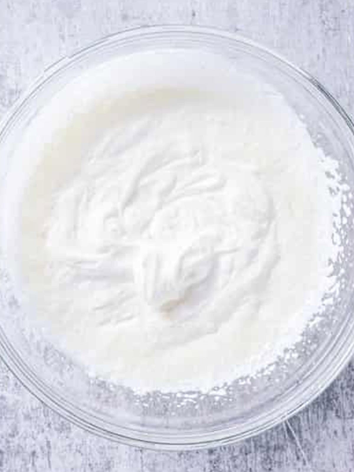 Fresh whipped cream beaten to soft peaks in a bowl for topping strawberry shortcake.