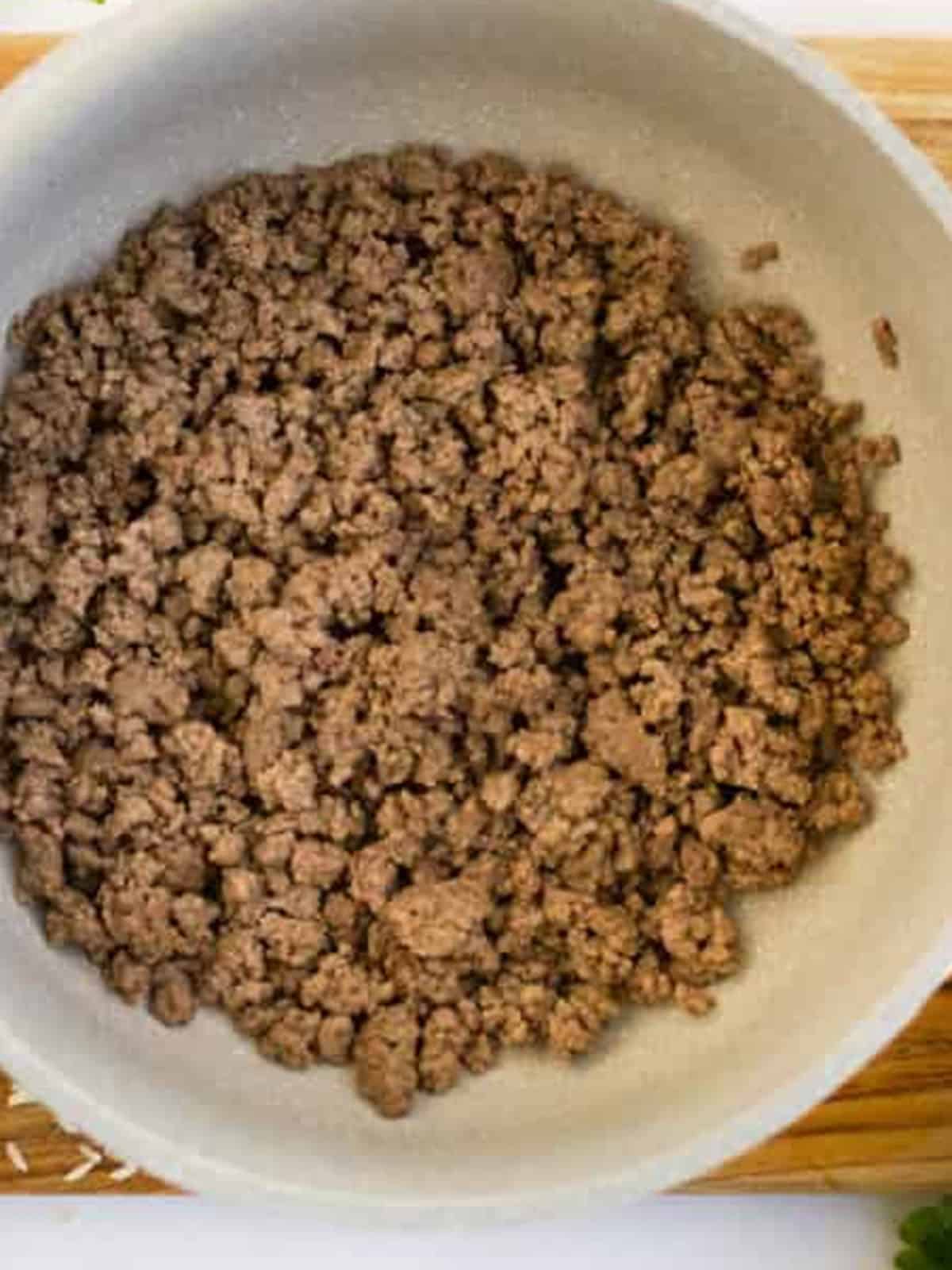 Browned ground beef in a Dutch oven for stuffed pepper soup.