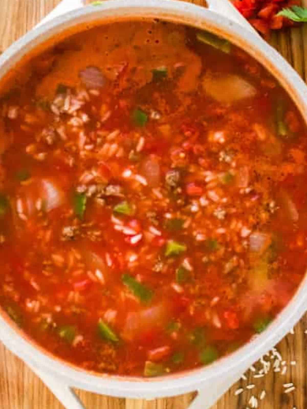 Finished stuffed pepper soup simmering in a pot with beef, rice, peppers, and tomato broth.