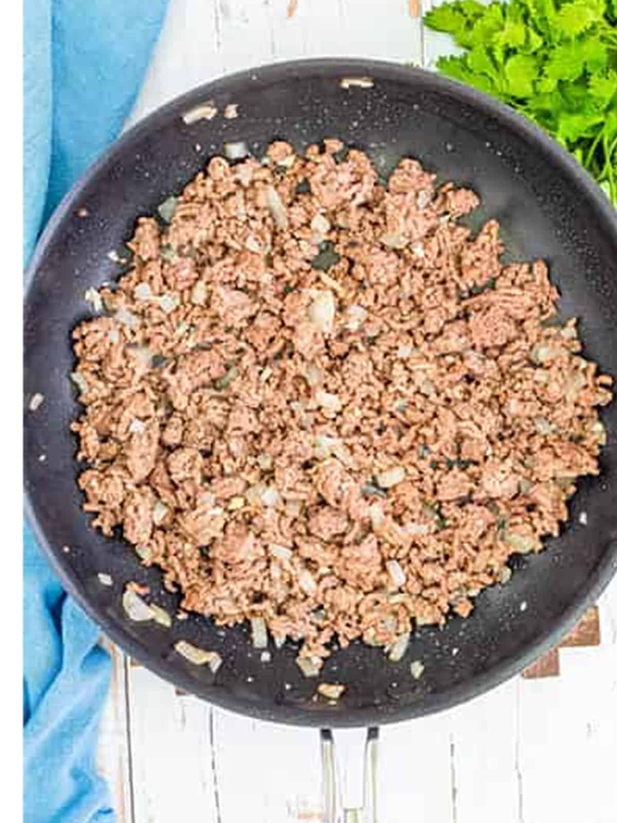 Ground beef browning in a skillet for stuffed peppers filling.