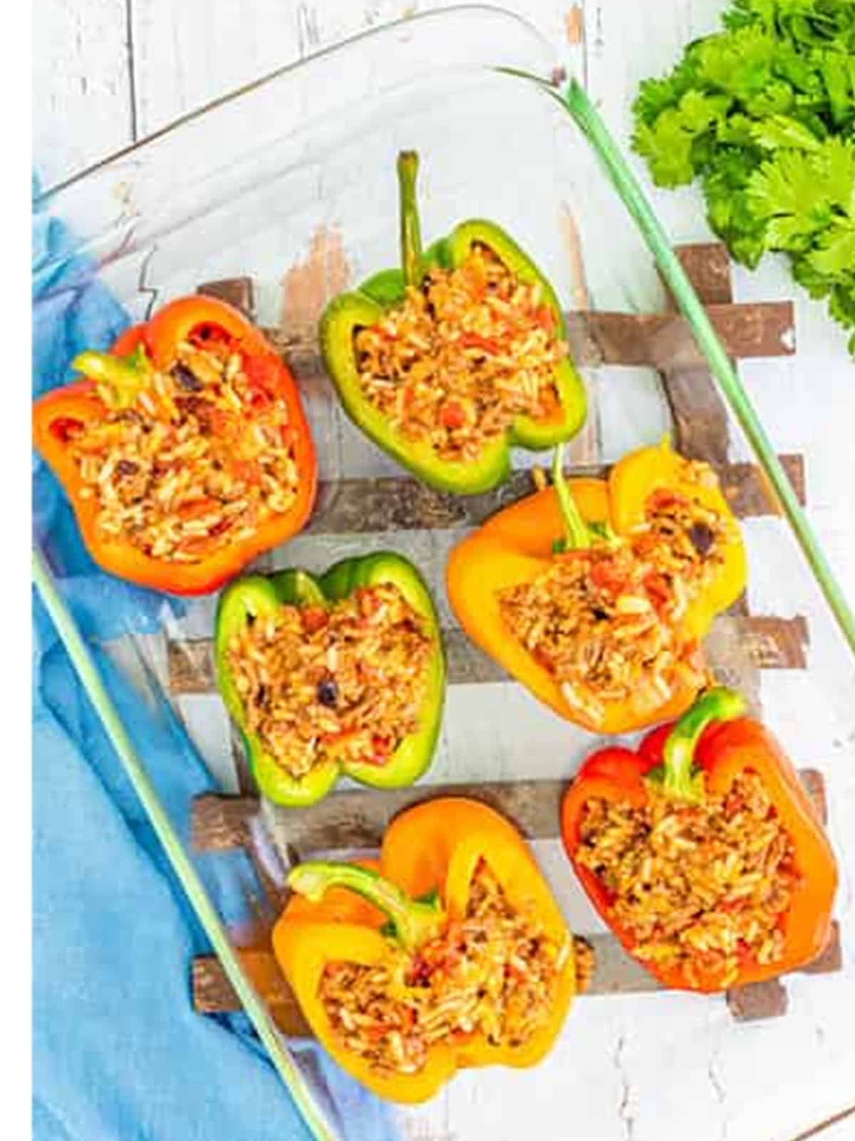 Spooning the beef and rice filling into halved bell peppers.