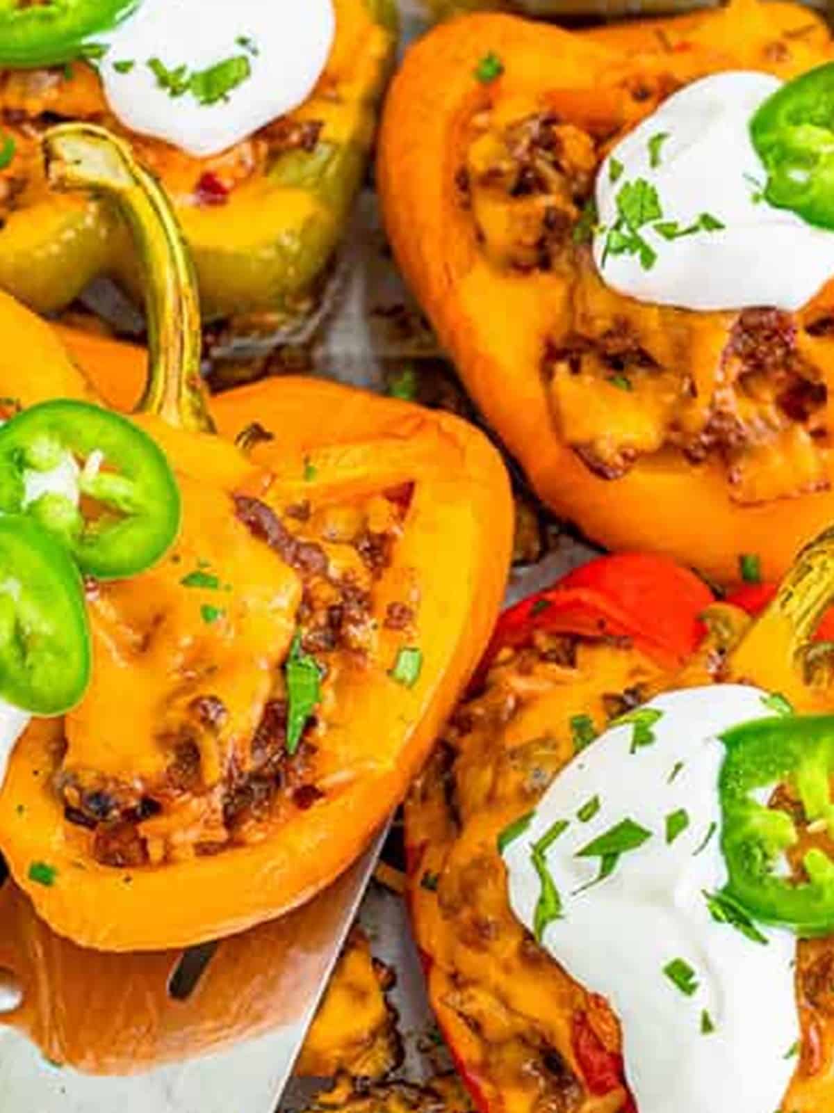 Finished Mexican stuffed peppers topped with sour cream and jalapeno.