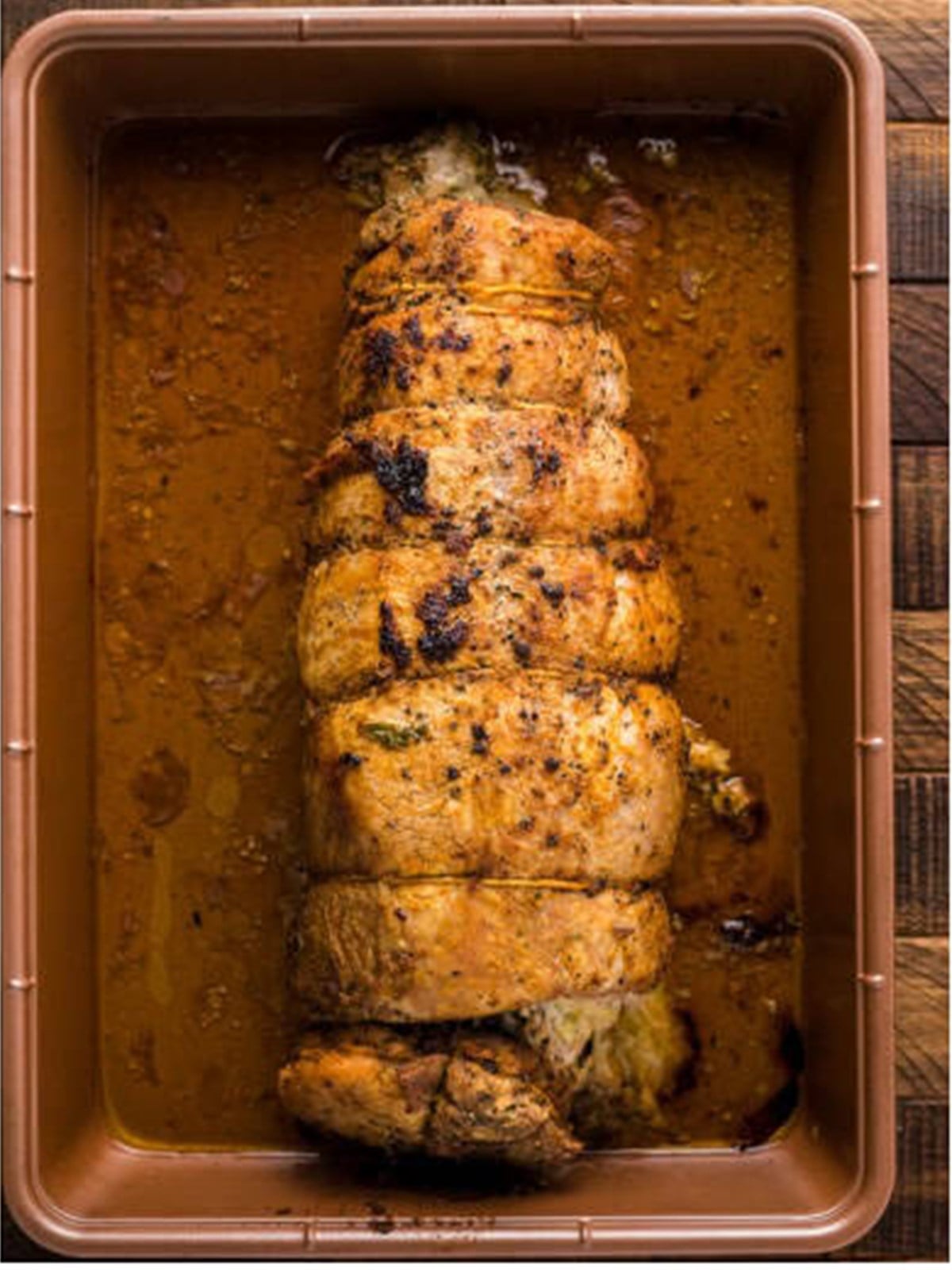 Stuffed pork loin roasting in a pan in the oven.