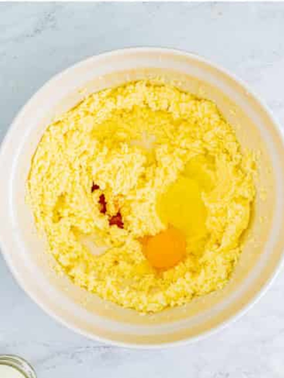 Adding an egg to creamed butter and sugar for cookie dough