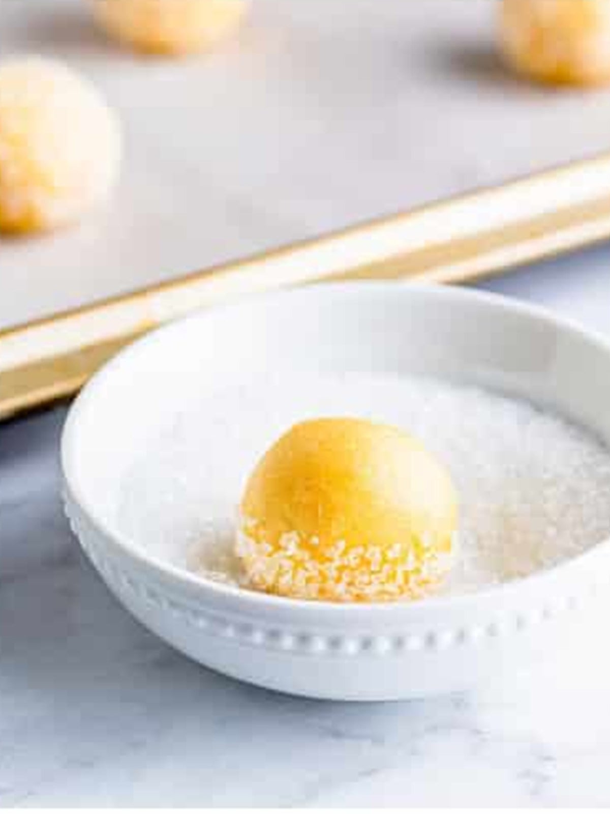 Dipping a sugar cookie dough ball in granulated sugar