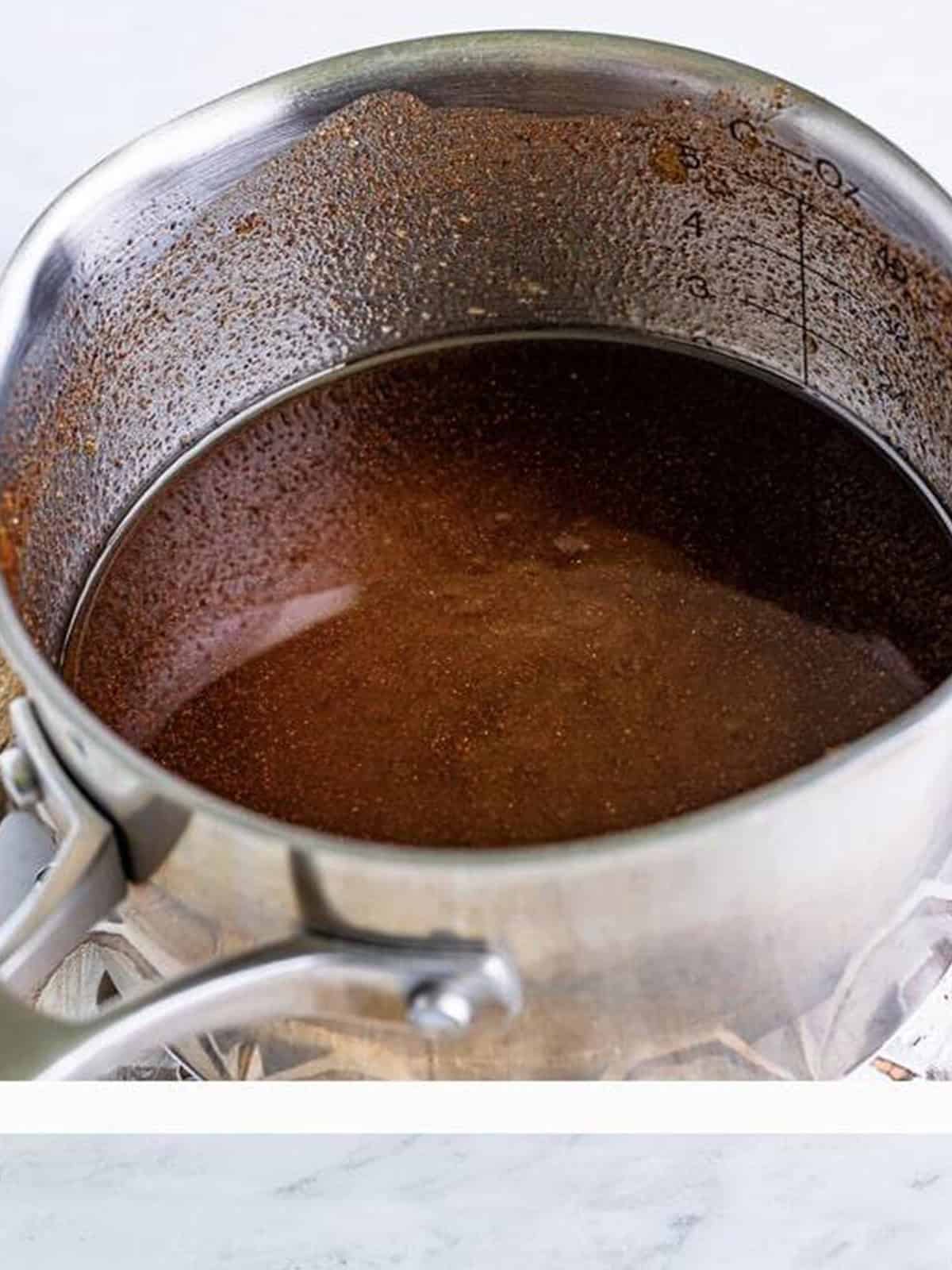 Melted butter, brown sugar, and cinnamon cooked into a sauce in a pot for Sweet Chex Mix.