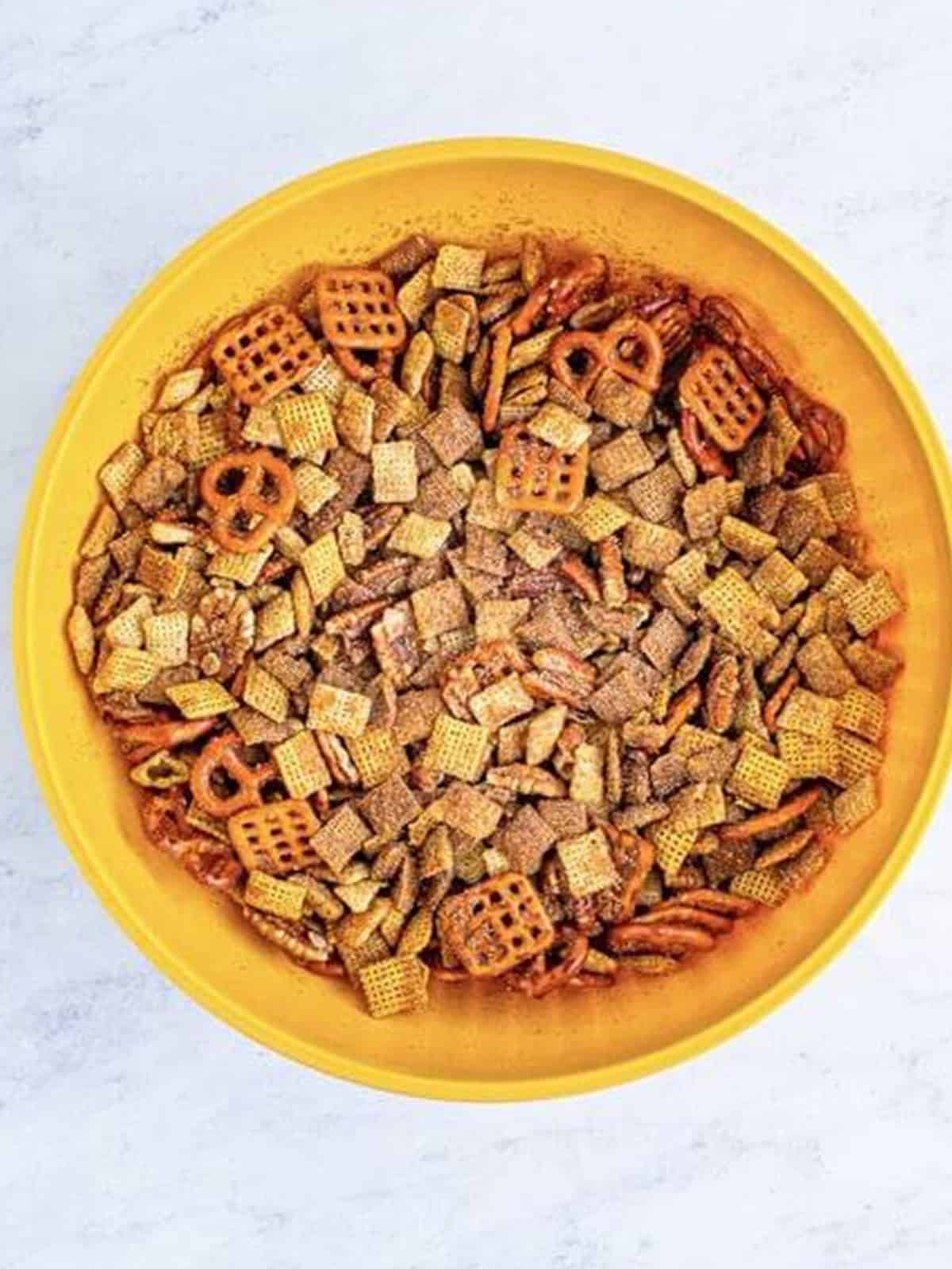 Finished Sweet Chex Mix tossed with cinnamon sugar topping in a bowl.