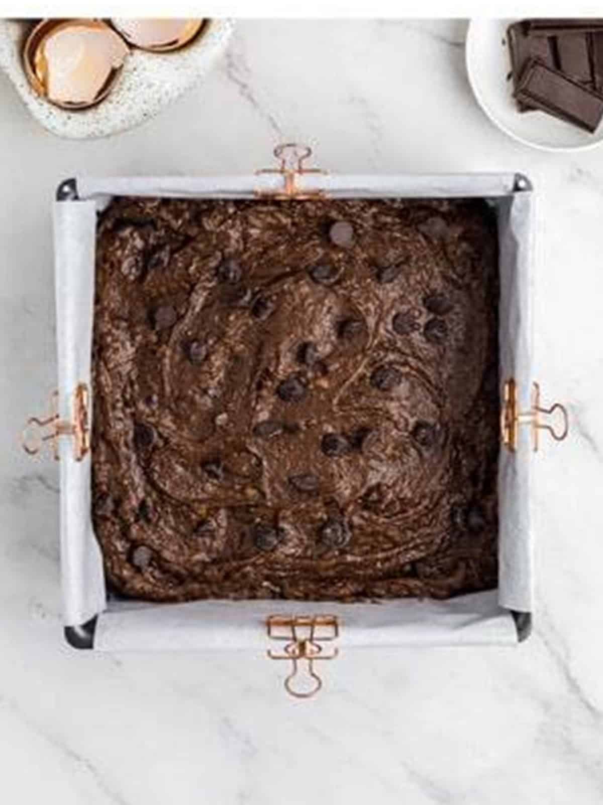 Sweet potato brownie batter spread into a parchment-lined square pan.