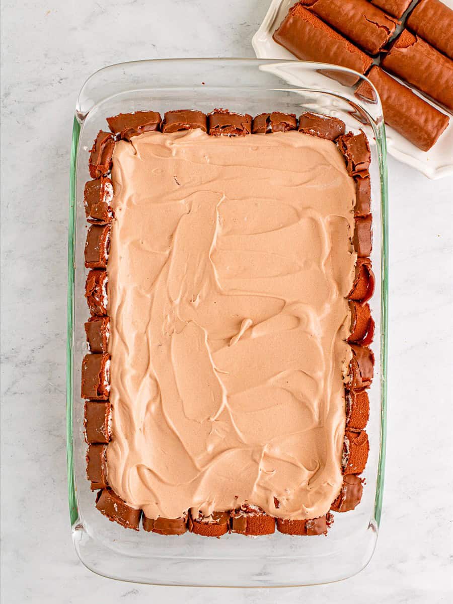 Chocolate pudding and cool whip layer spread over the swiss rolls.