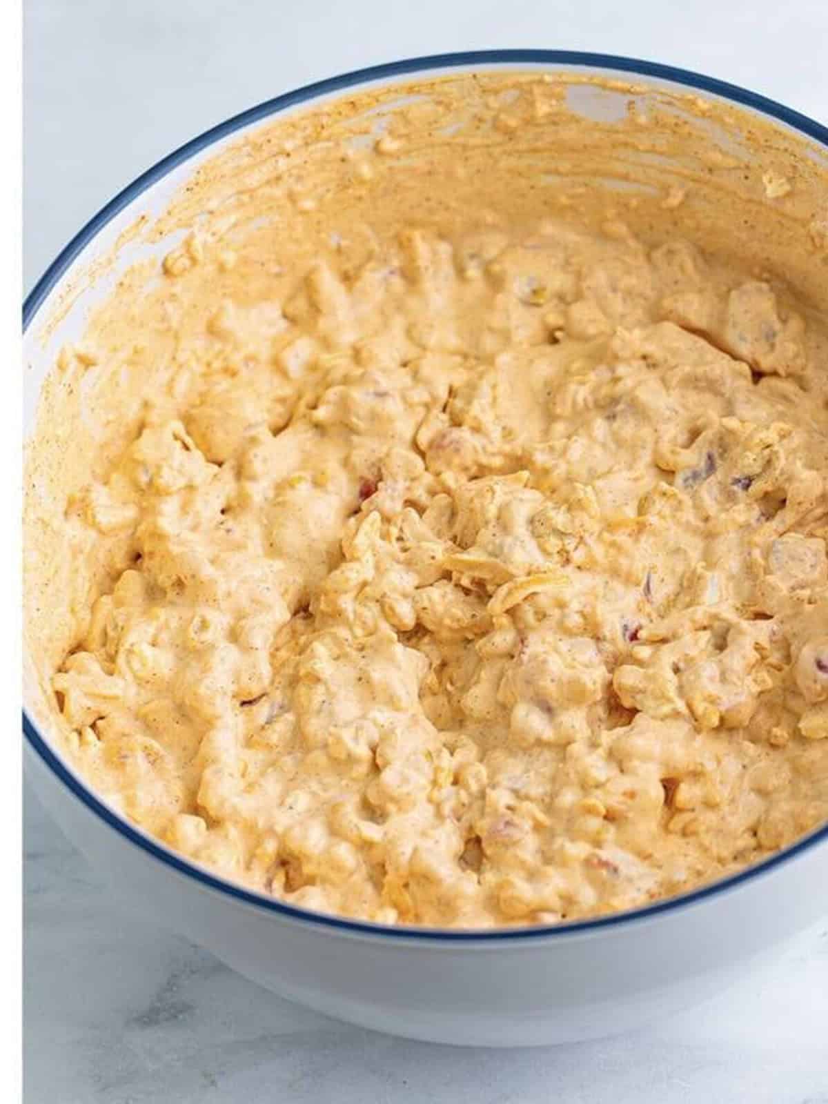 Creamy taco dip mixed together in a bowl with a hand mixer.
