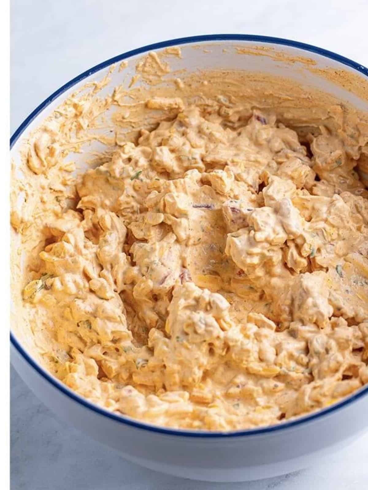 Finished cold creamy taco dip in a bowl ready to serve with tortilla chips.