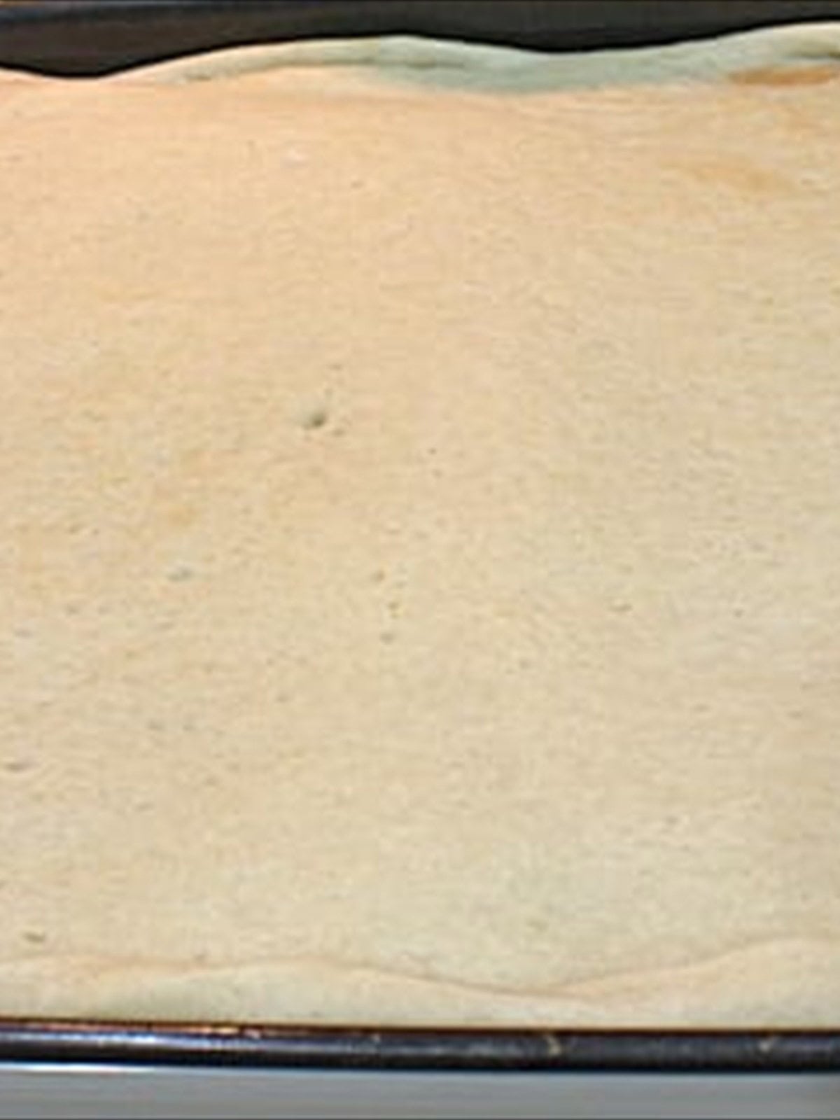 A pre-baked pizza crust on a baking sheet ready to be topped.