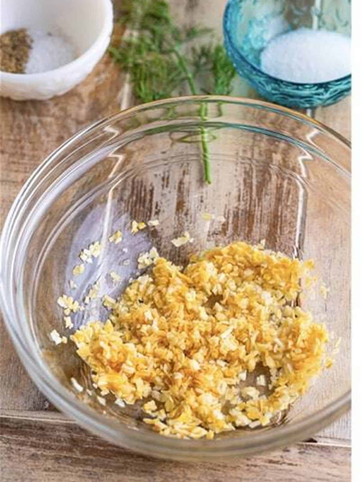 Dried minced onion and lemon juice stirred together in a glass bowl to make tartar sauce.