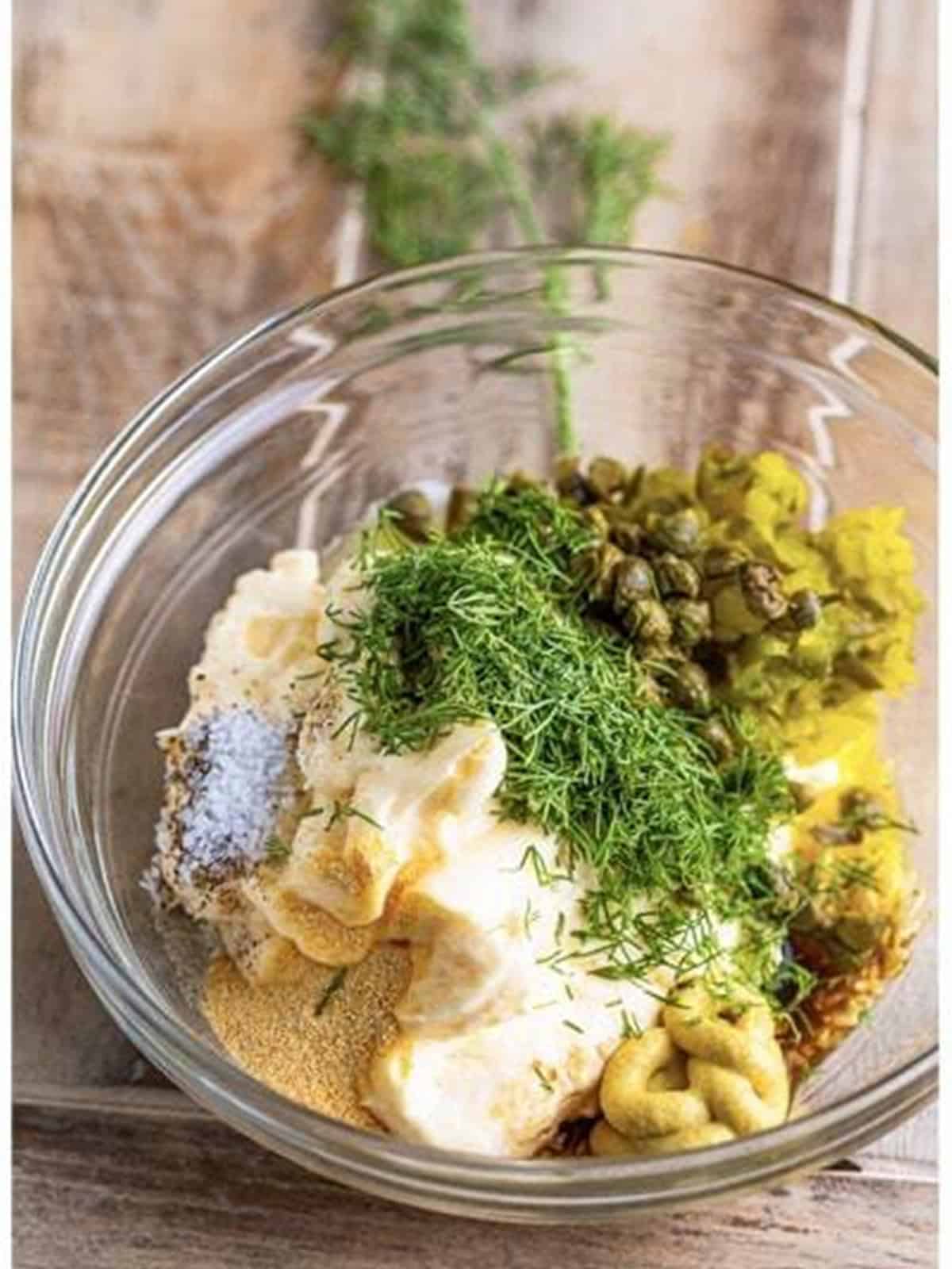 Mayonnaise, relish, capers, dill, and seasonings added to the bowl for tartar sauce.