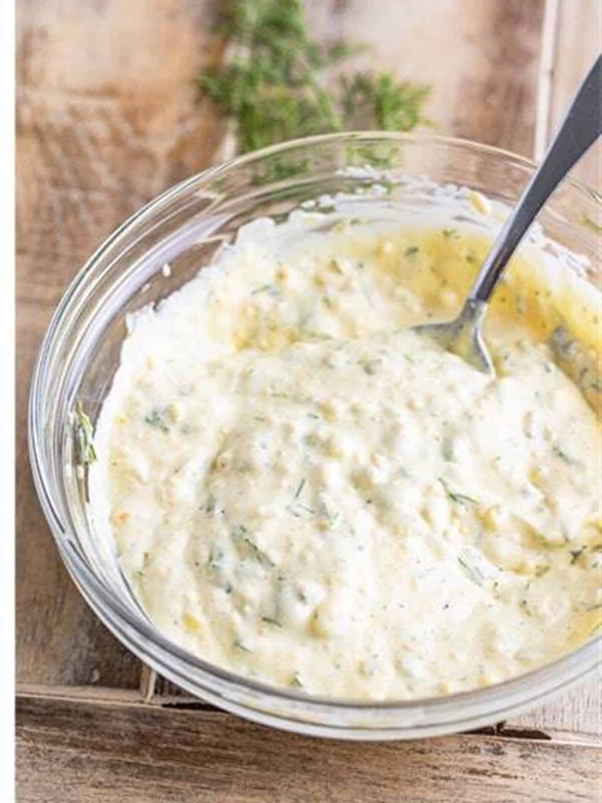Creamy homemade tartar sauce whisked smooth in a glass bowl.