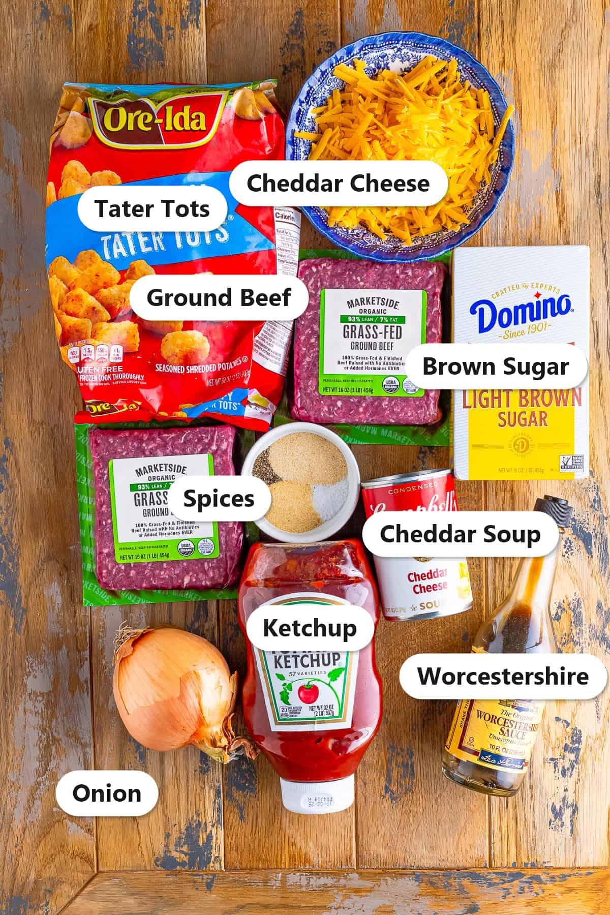 Labeled ingredients for tater tot casserole including ground beef, tater tots, cheddar cheese, cheddar soup, ketchup, Worcestershire, brown sugar, onion, and spices.