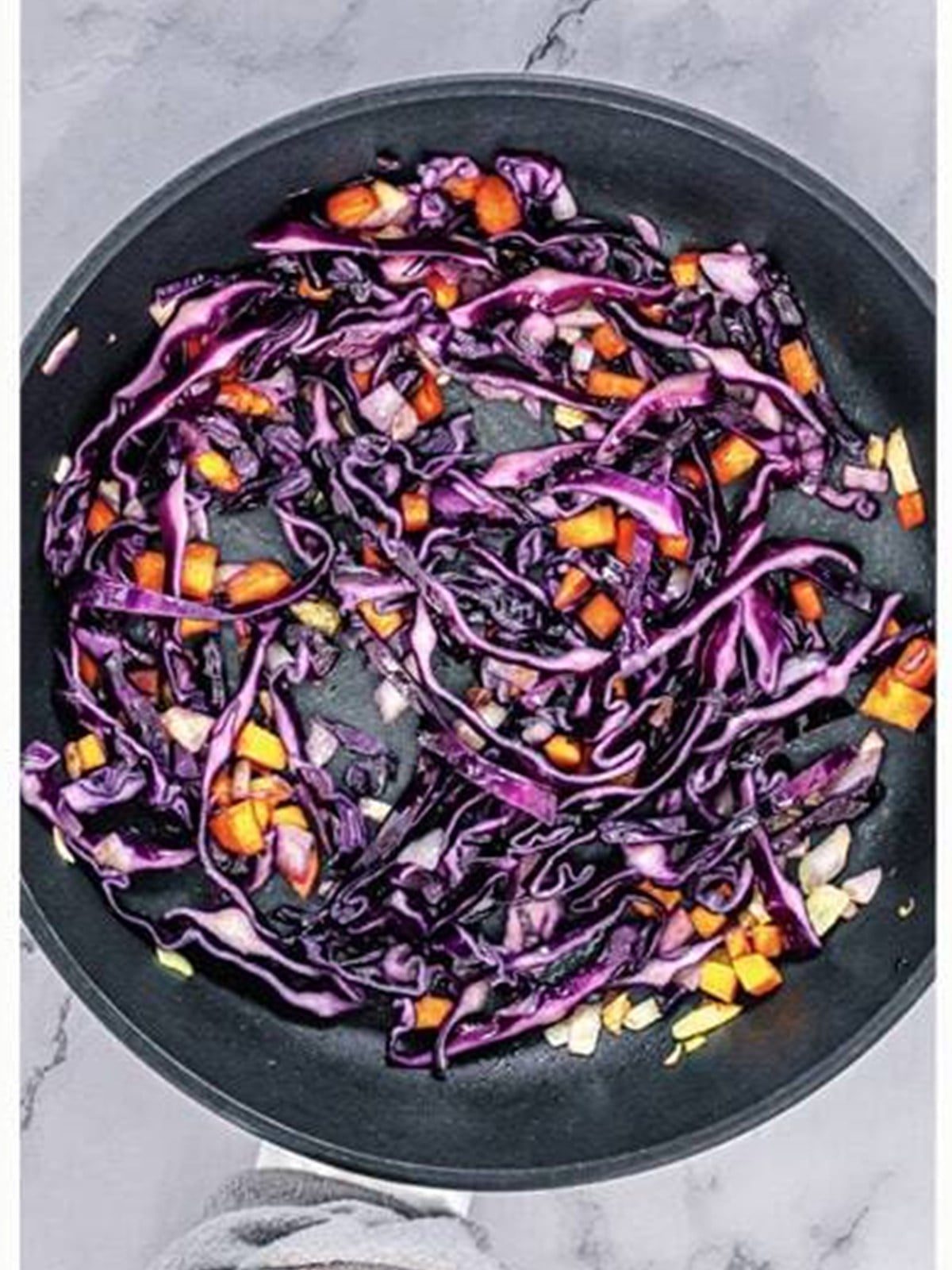 Shredded red cabbage added to the sauteing vegetables.