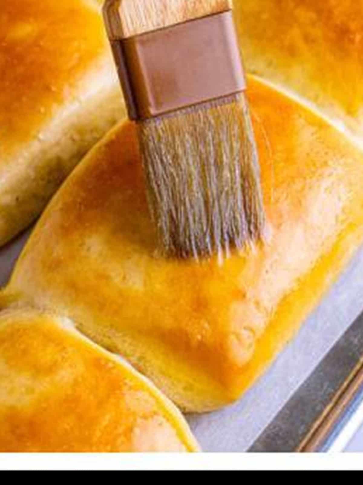 Brushing melted butter over golden baked Texas Roadhouse rolls.