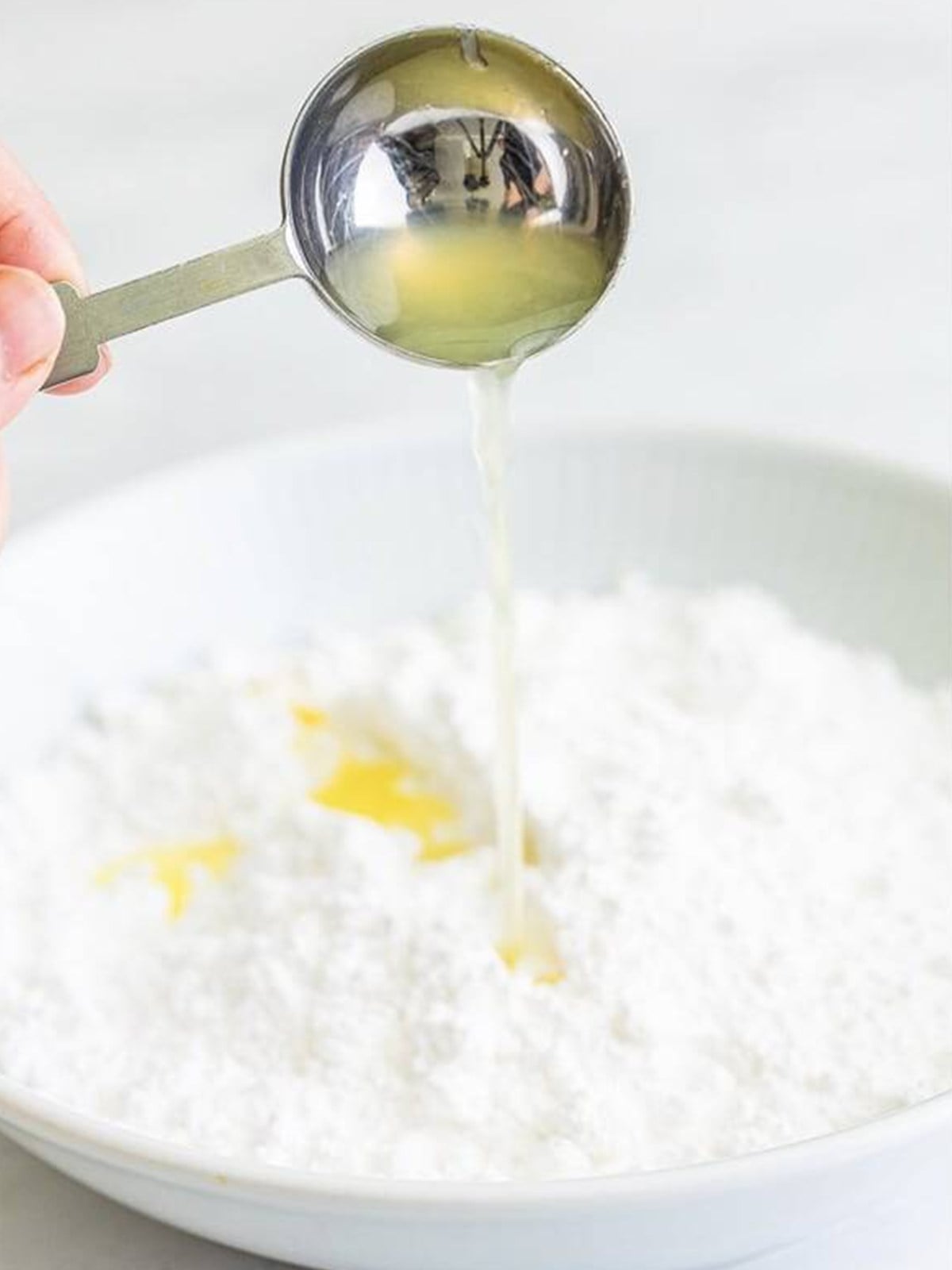 Lemon juice poured into powdered sugar to make a glaze for thumbprint cookies.