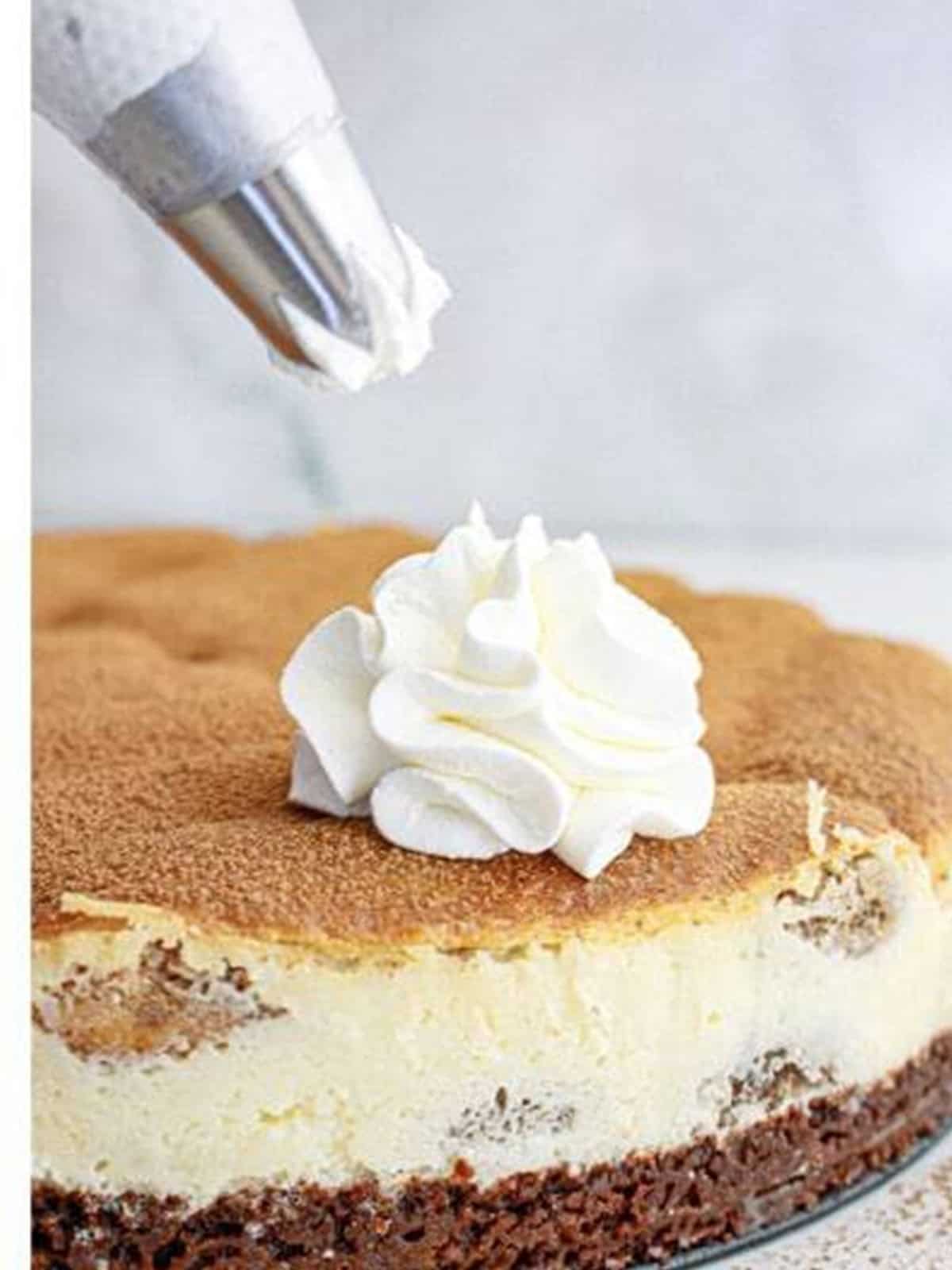 Piping whipped cream swirls on top of the finished tiramisu cheesecake.