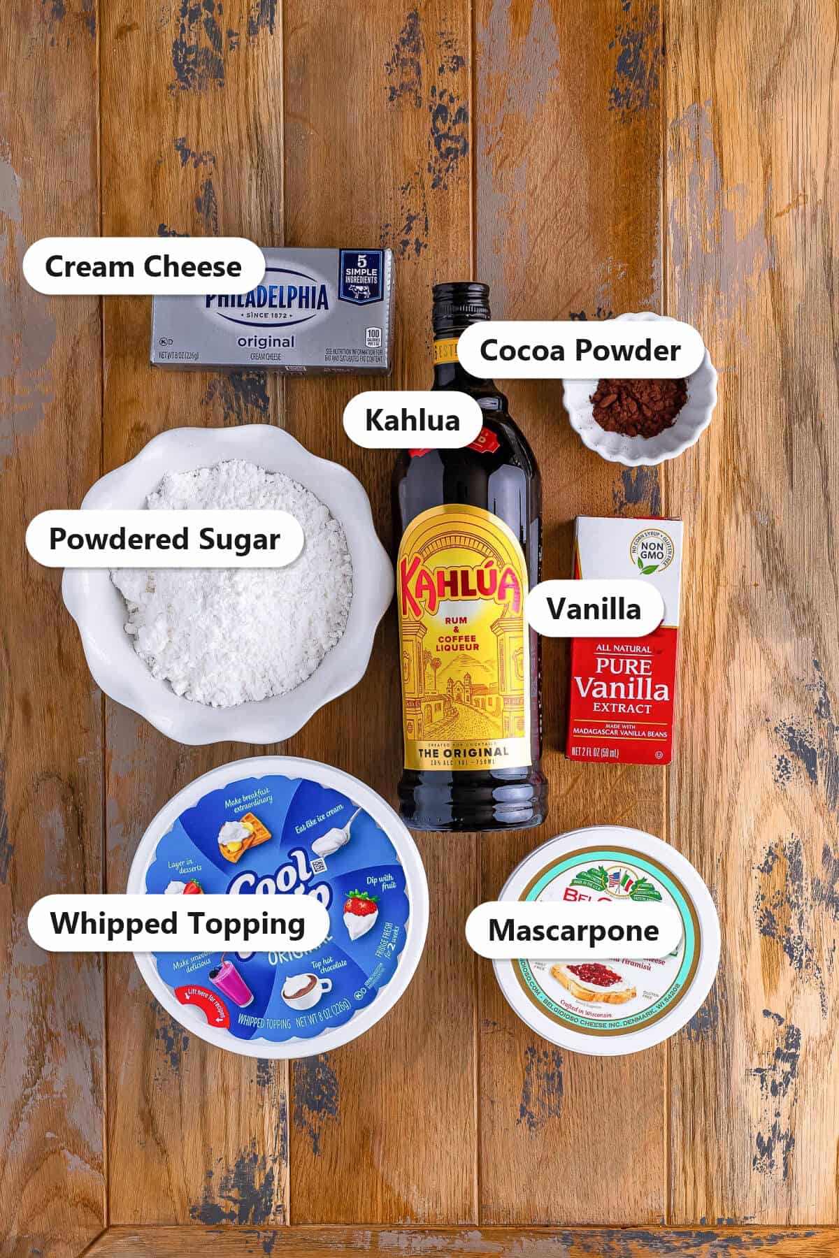 Labeled ingredients for tiramisu dip with Kahlua including mascarpone, cream cheese, powdered sugar, Kahlua, vanilla, whipped topping, and cocoa powder.