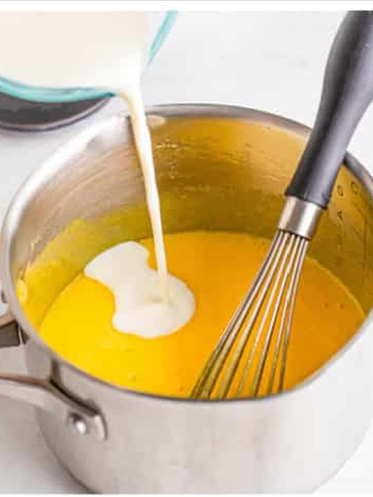 Whisking milk into the egg custard for tiramisu recipe.