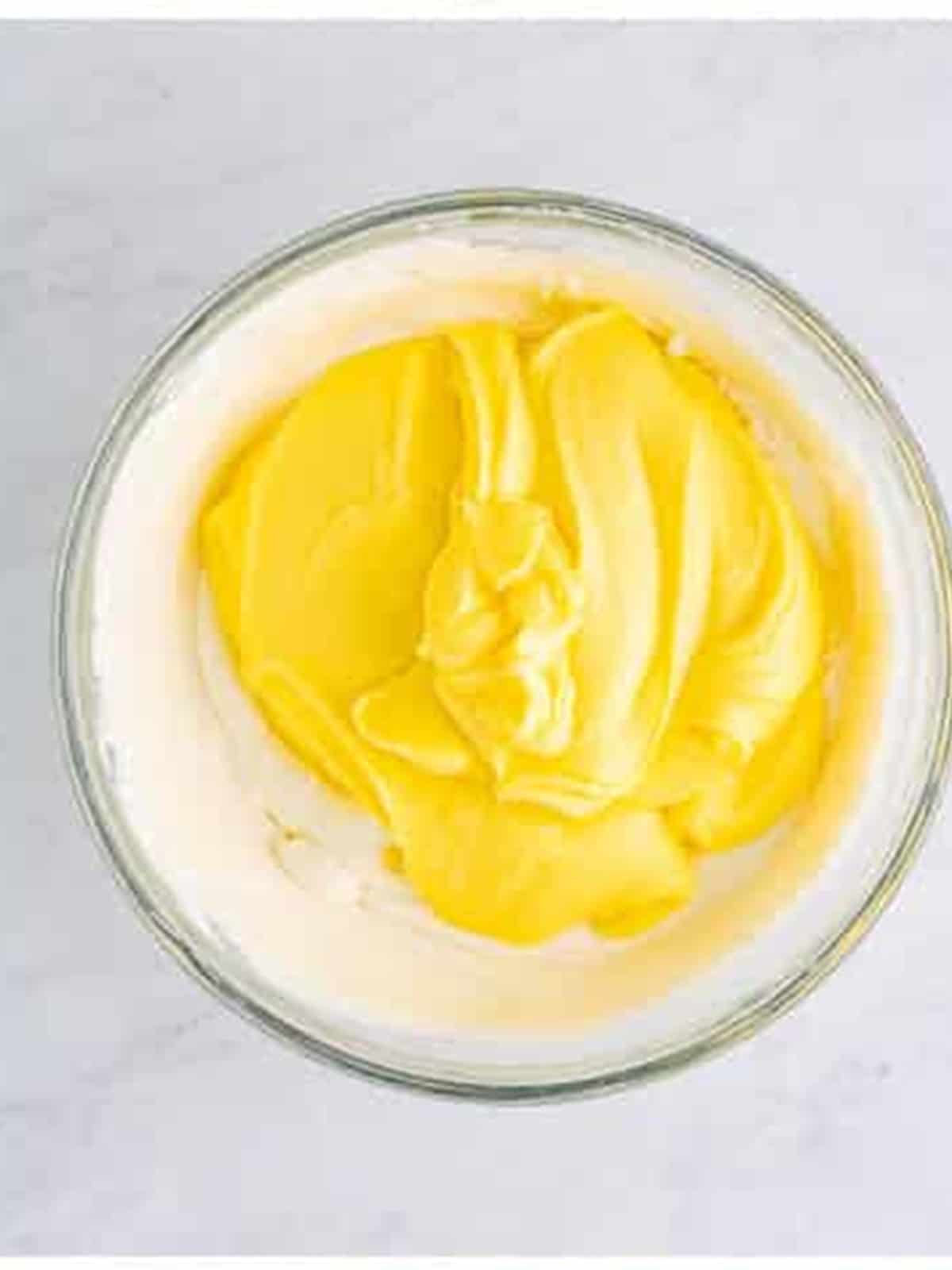 Adding cooled custard to mascarpone cheese in a bowl for tiramisu recipe.