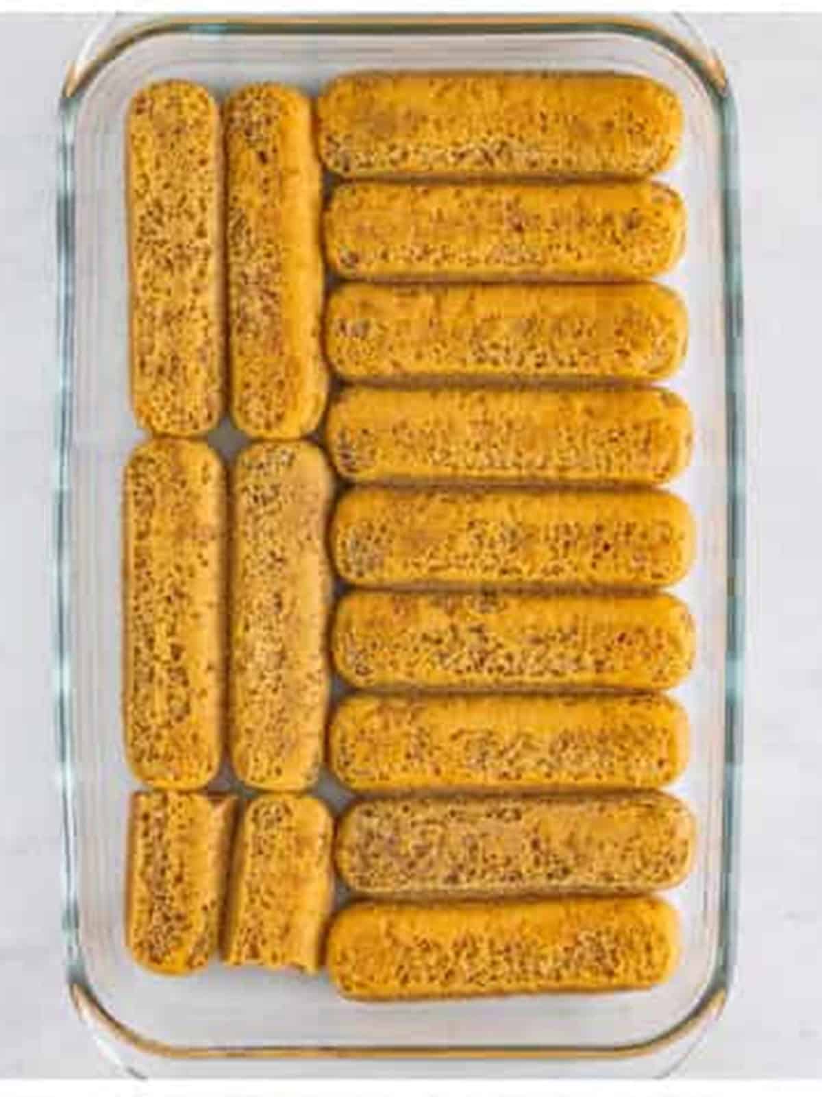 Layering dipped lady fingers in a baking dish for tiramisu recipe.