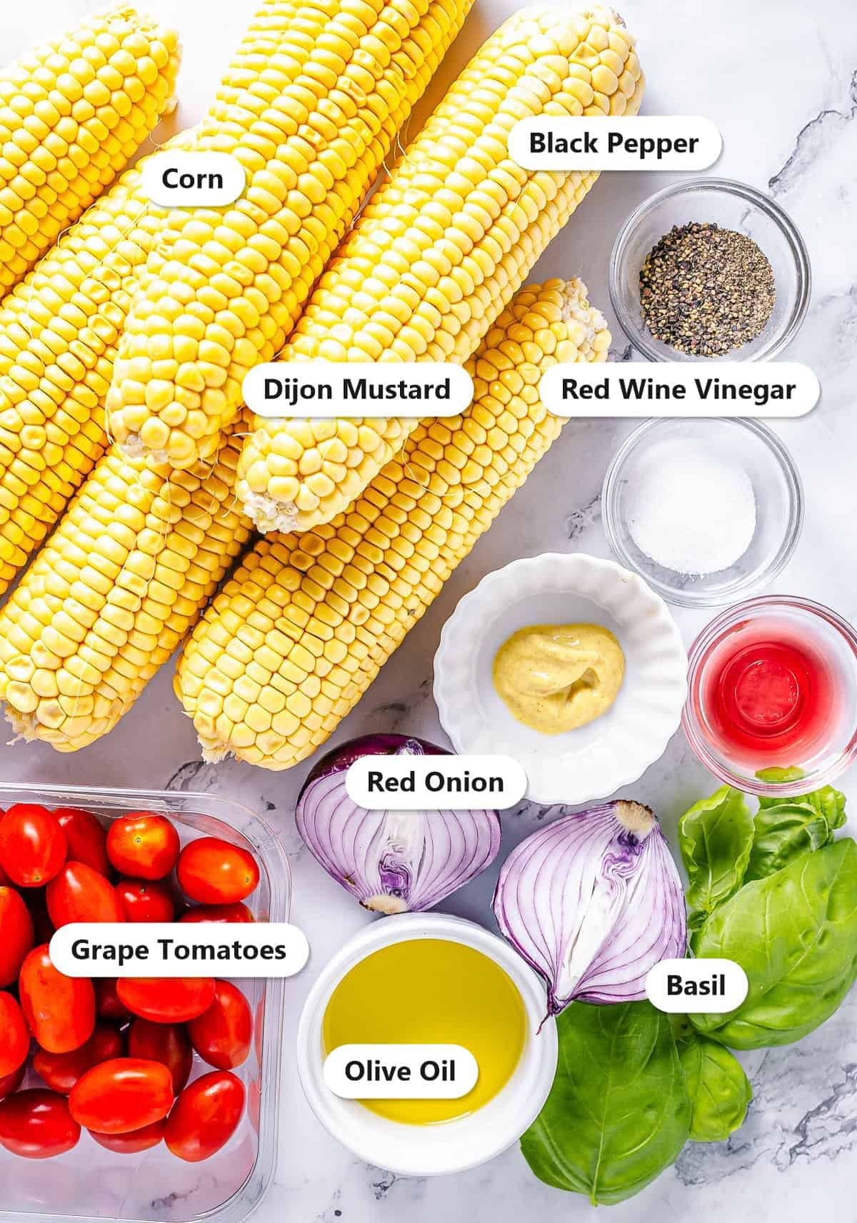 Labeled ingredients for corn and tomato salad including corn, grape tomatoes, red onion, basil, olive oil, red wine vinegar, and dijon mustard.