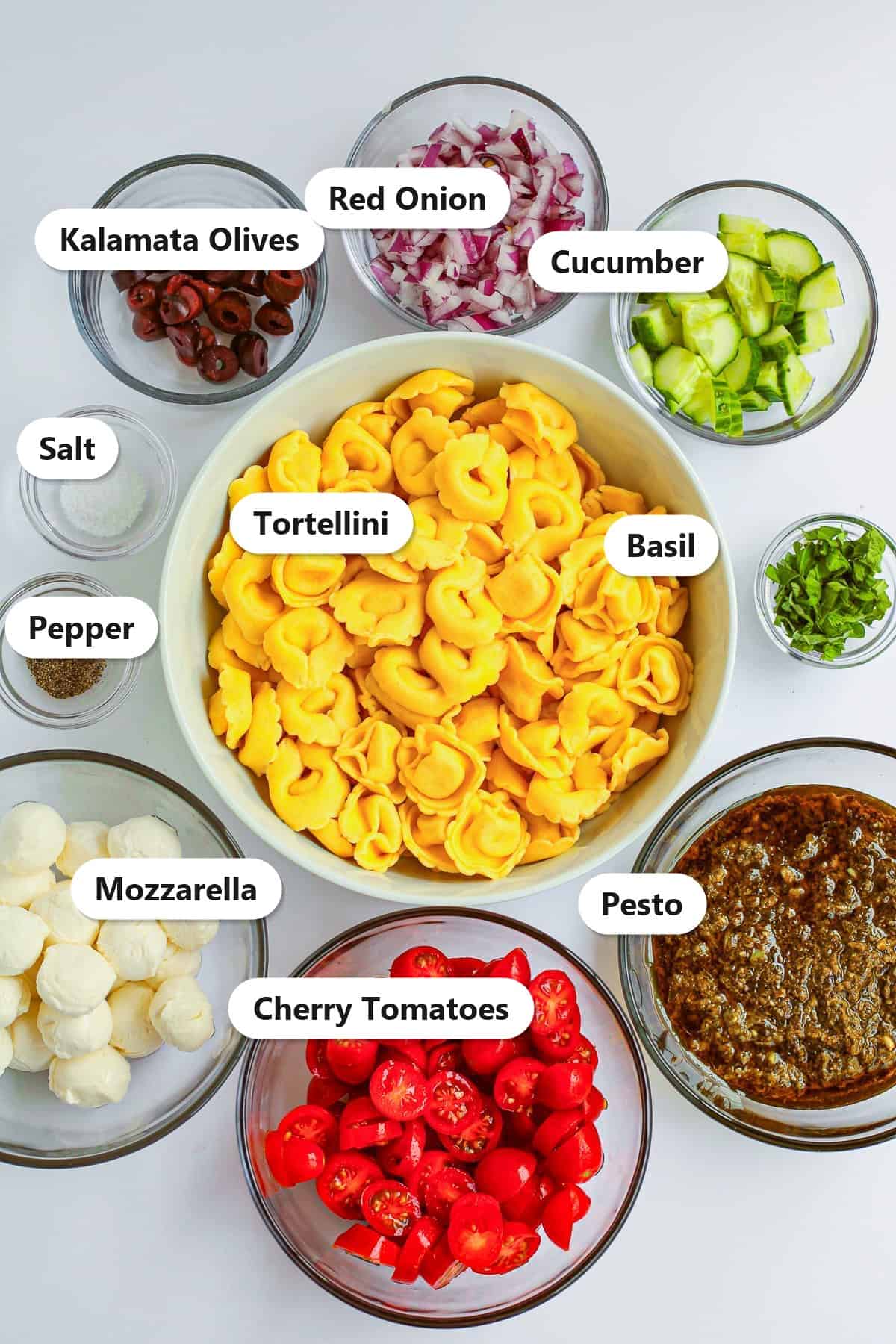 Labeled ingredients for Tortellini Pasta Salad including cheese tortellini, pesto, mozzarella, and cherry tomatoes.