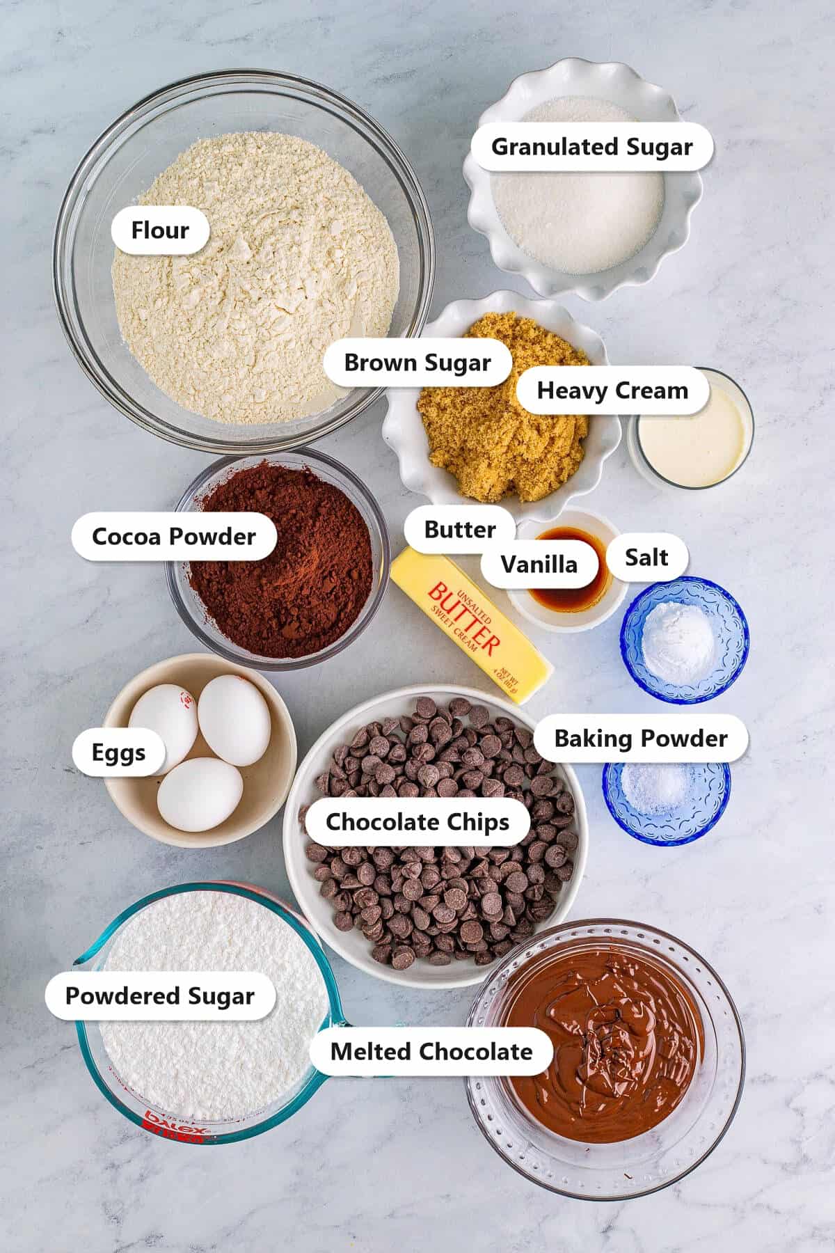 Labeled ingredients for triple chocolate cookies including flour, cocoa powder, butter, sugars, eggs, chocolate chips, and melted chocolate for the frosting.
