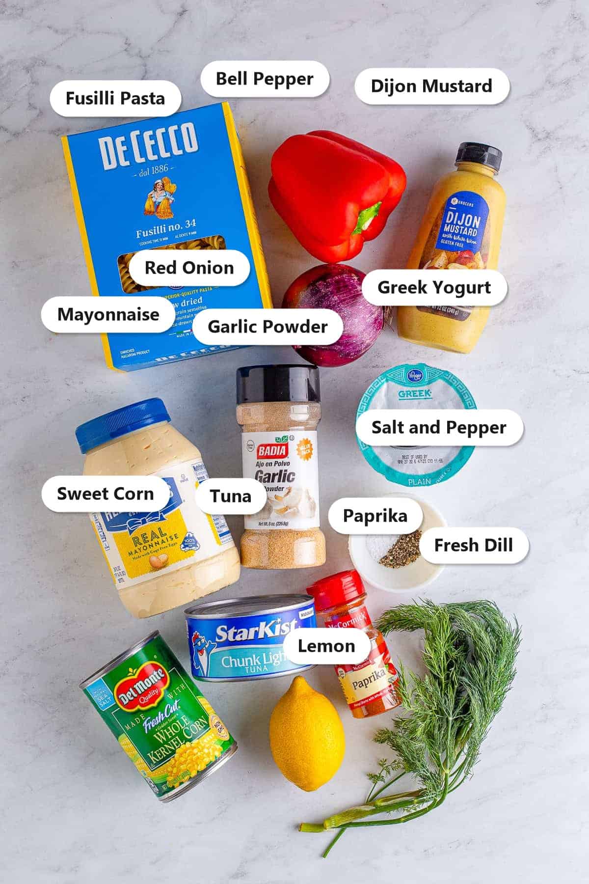 Labeled ingredients for tuna pasta salad including fusilli pasta, tuna, bell pepper, sweet corn, red onion, dill, mayonnaise, Greek yogurt, and dijon mustard.