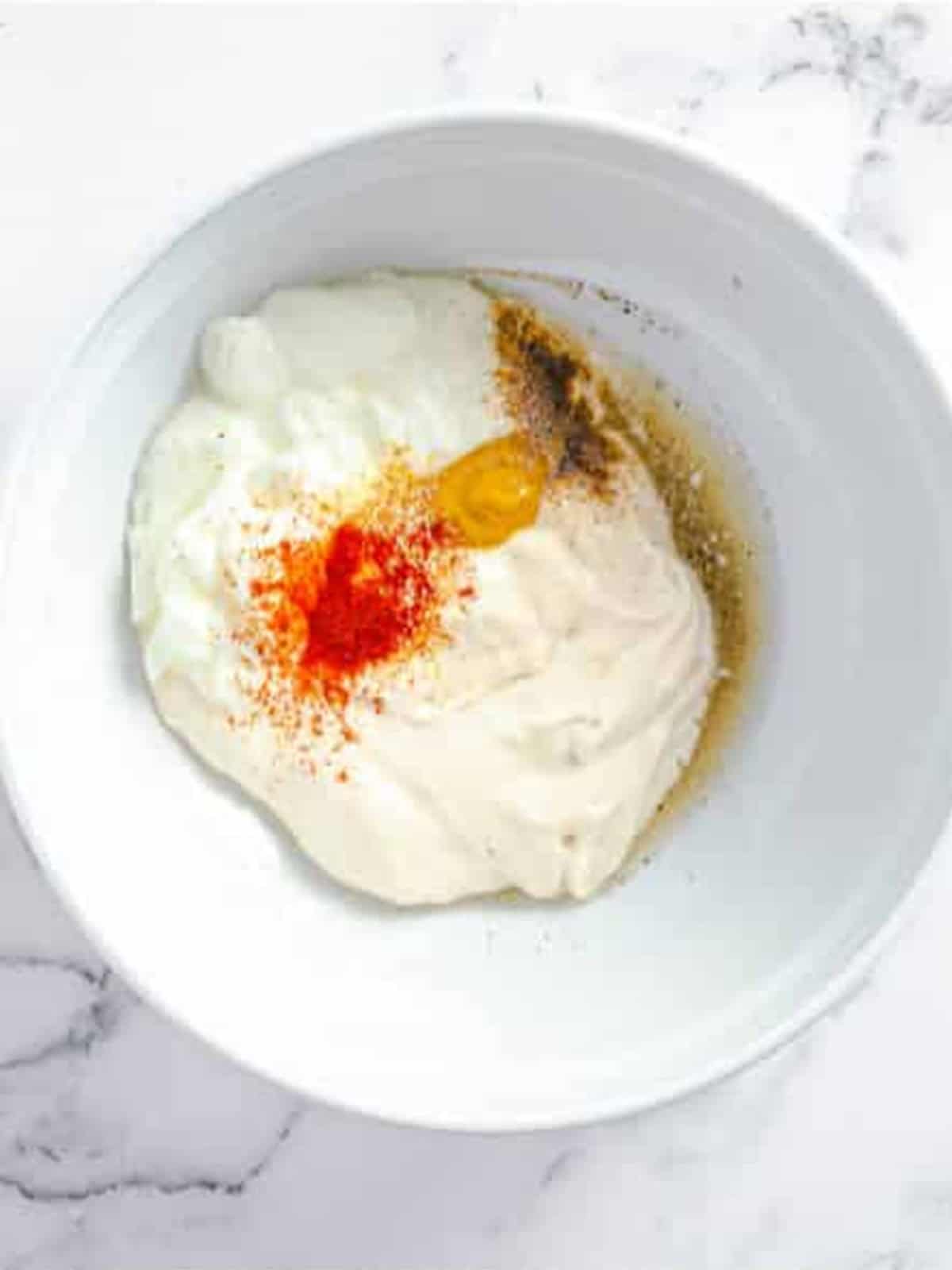 Mayonnaise, Greek yogurt, dijon, and seasonings combined in a bowl for the creamy dressing.
