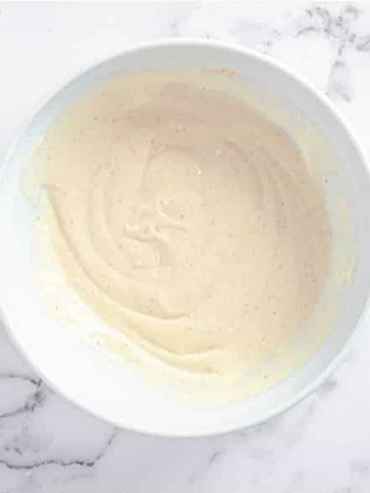 The creamy dressing whisked smooth in a glass bowl.