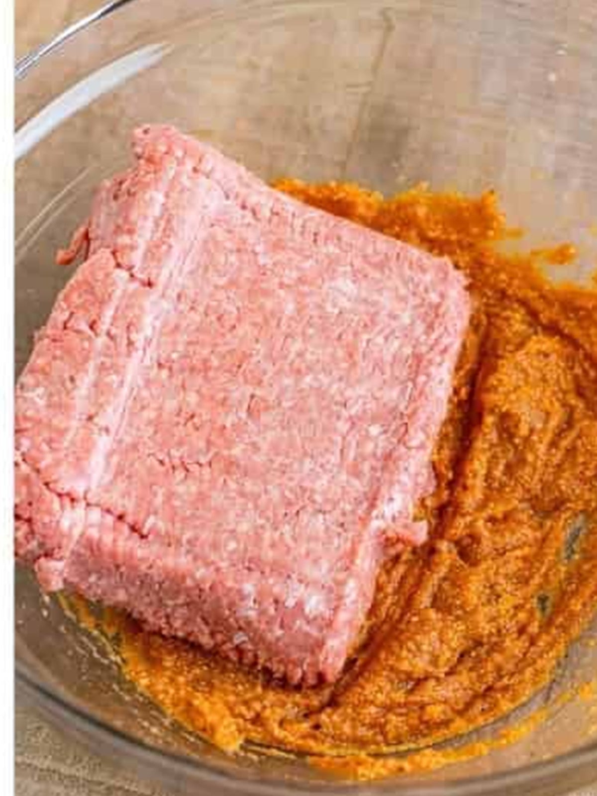 Ground turkey added to the seasoned sauce mixture in a bowl for turkey burgers.