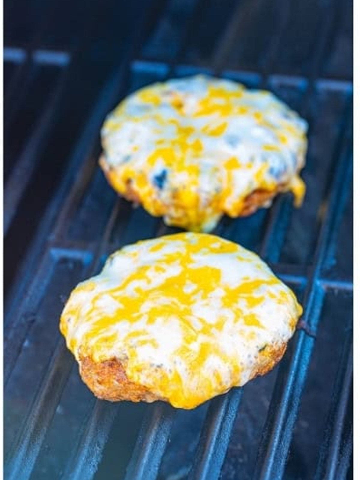 Melted cheese topping turkey burger patties on the grill.