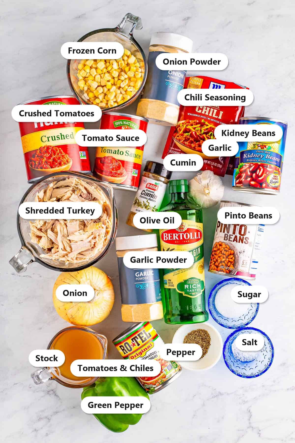 Labeled ingredients for turkey chili including shredded turkey, kidney and pinto beans, tomatoes, corn, chili seasoning, and spices.