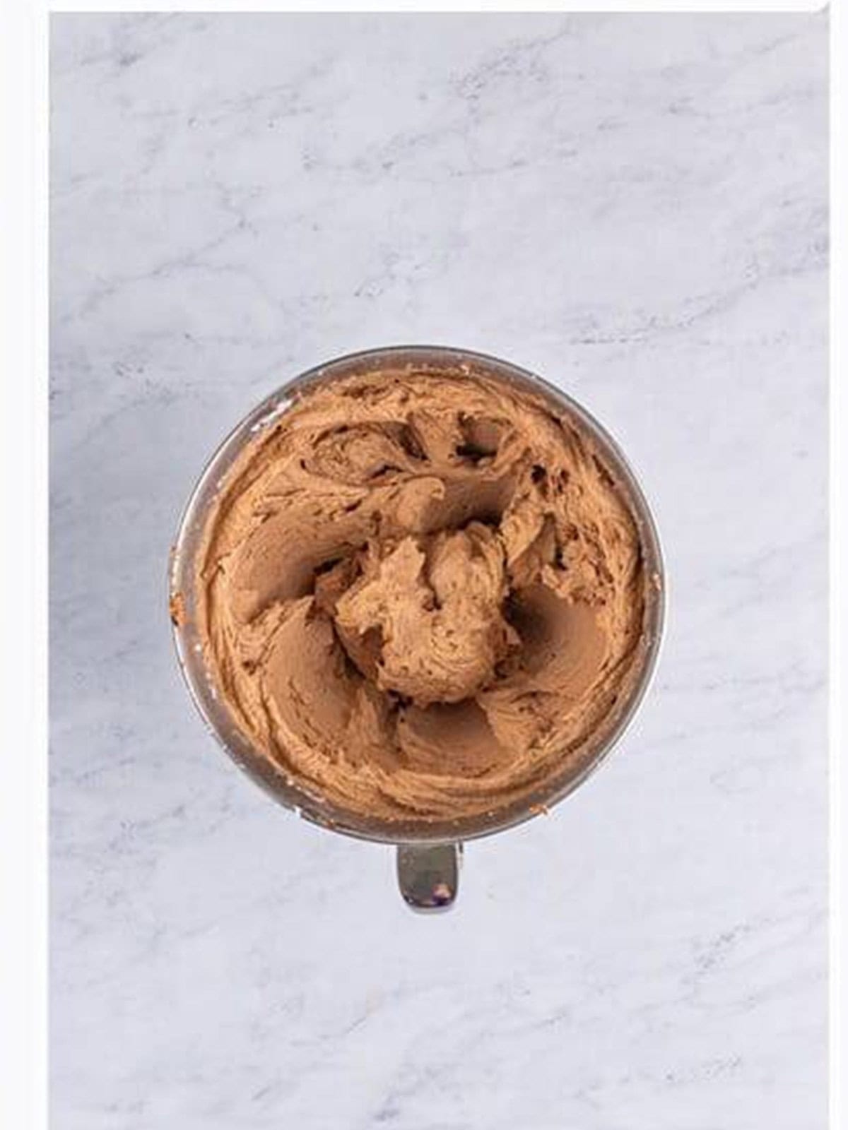 Whipped chocolate frosting in a stand mixer bowl.