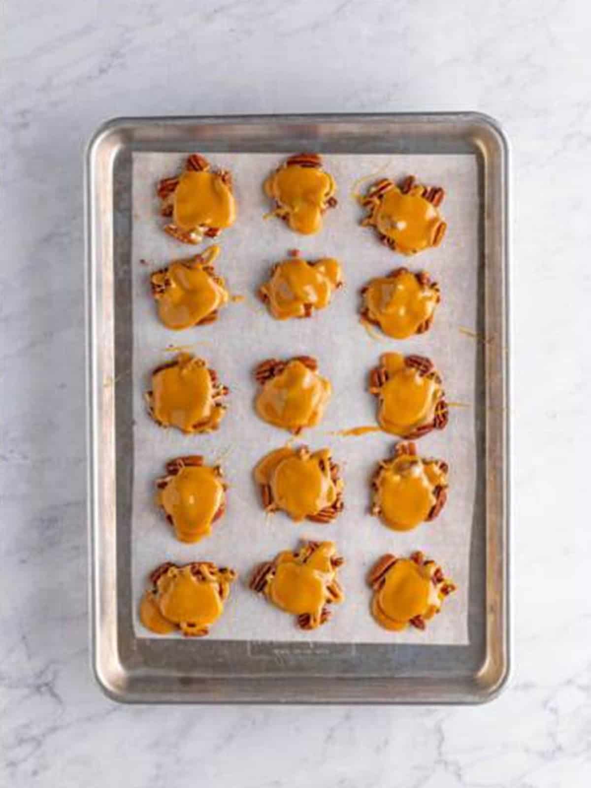Warm caramel drizzled over the piles of pecans on the tray.