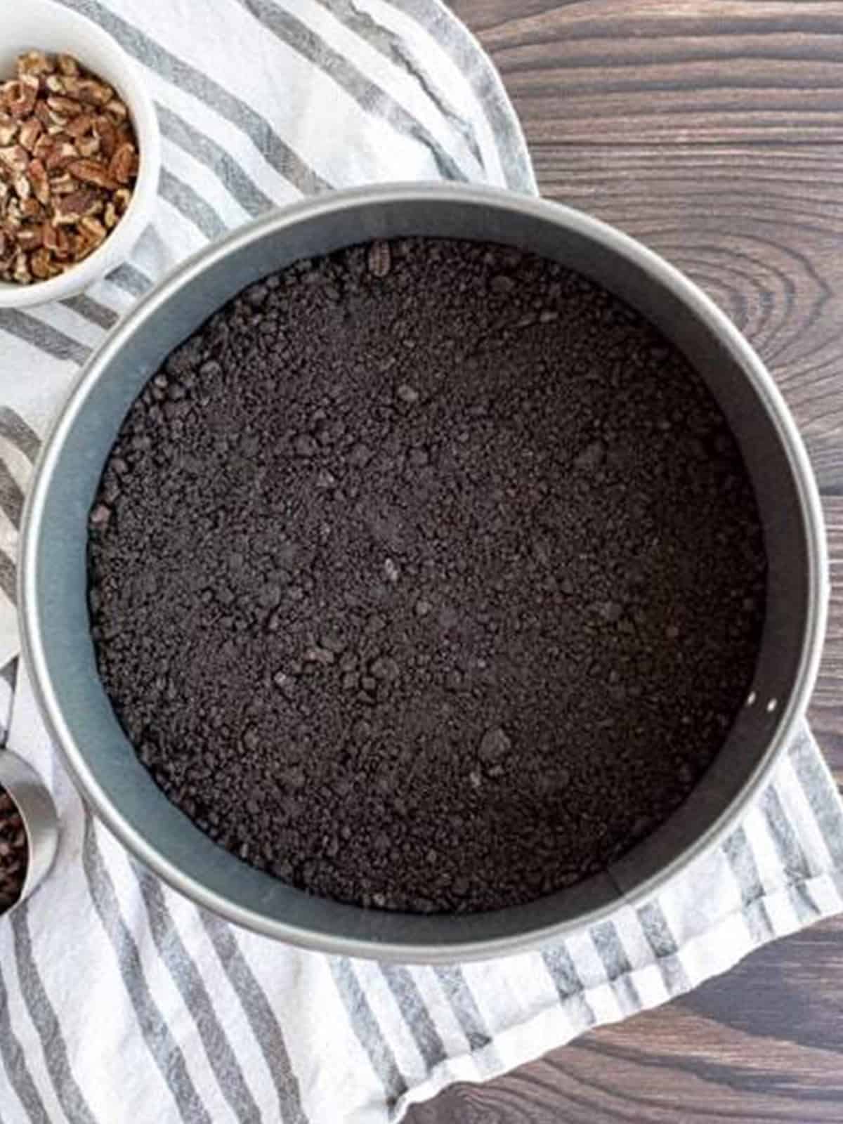 Graham cracker crust pressed into a springform pan for turtle cheesecake.