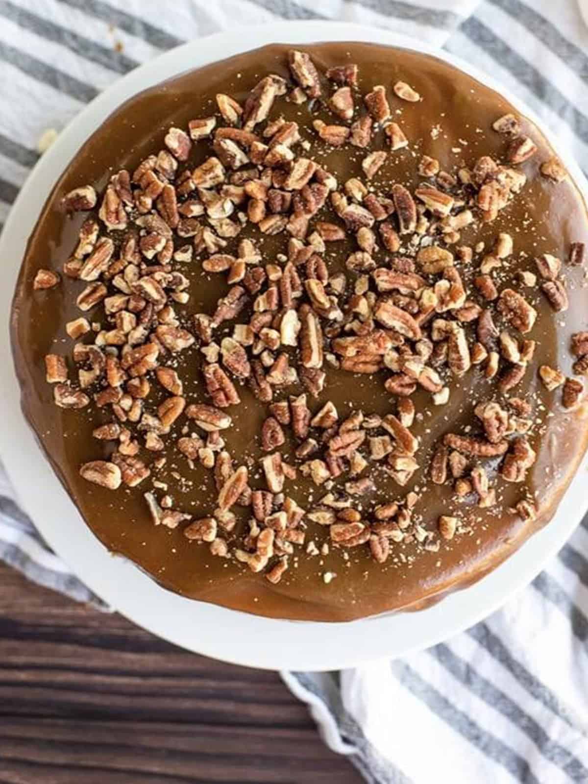 Pouring caramel and chopped pecans over the baked cheesecake.