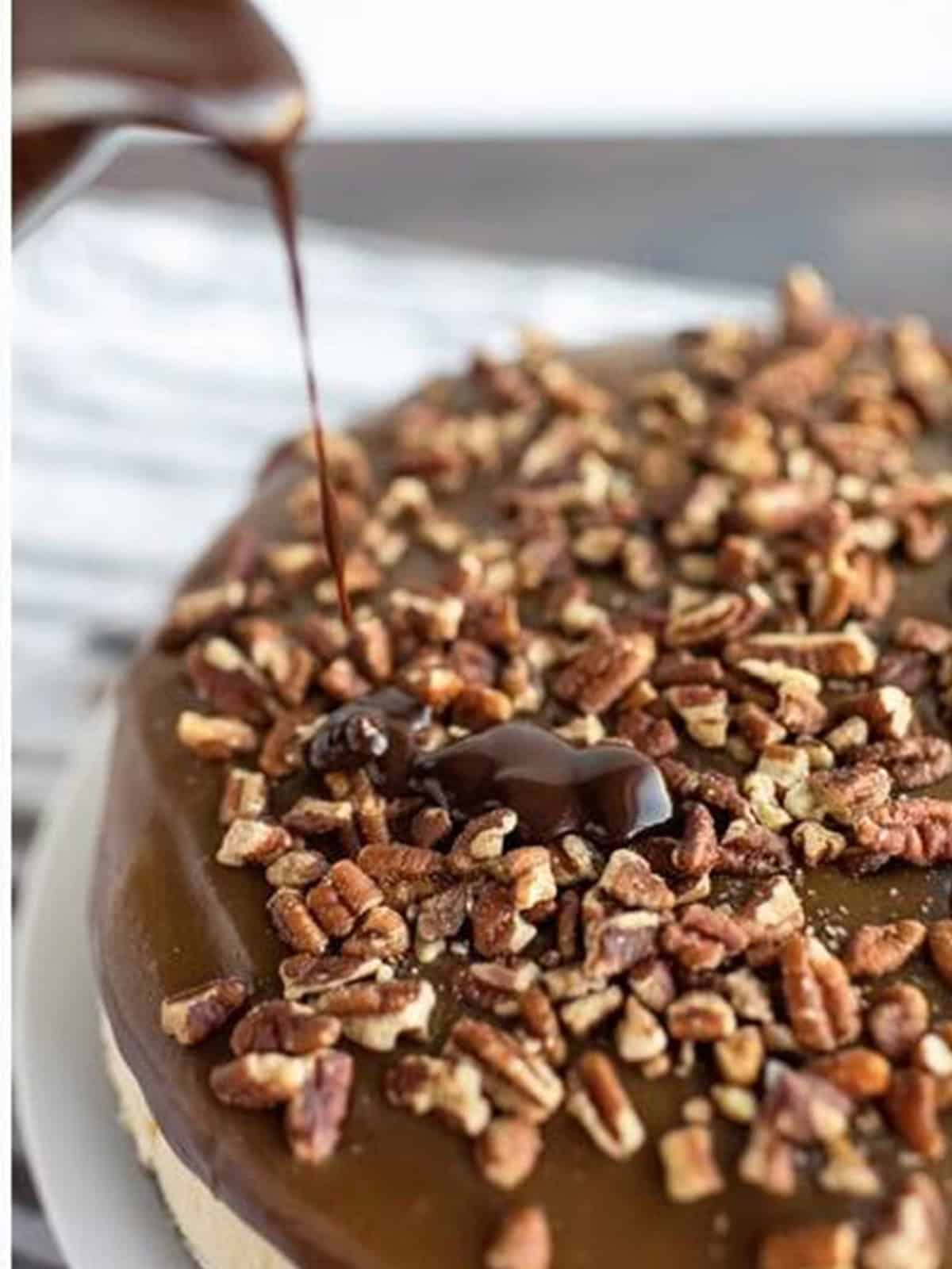 Drizzling chocolate ganache over the caramel and pecan topped turtle cheesecake.