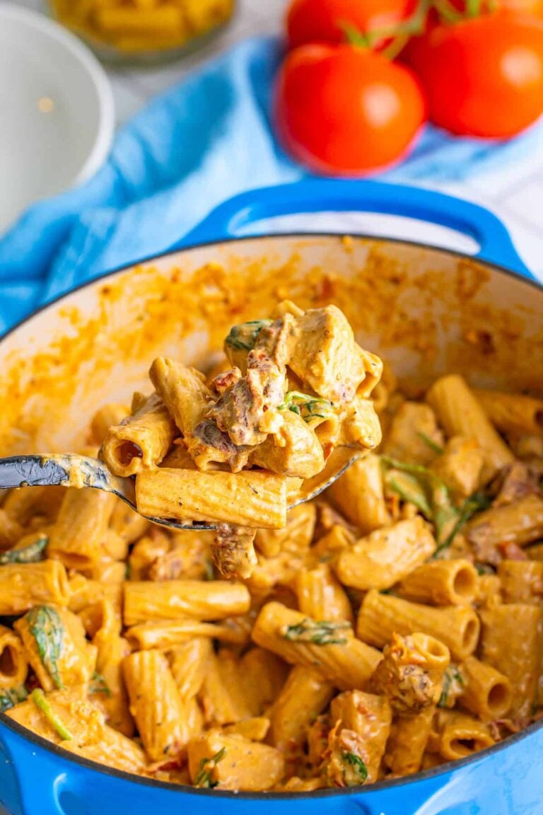 A pot of creamy Tuscan chicken pasta with rigatoni, spinach, and sundried tomatoes.