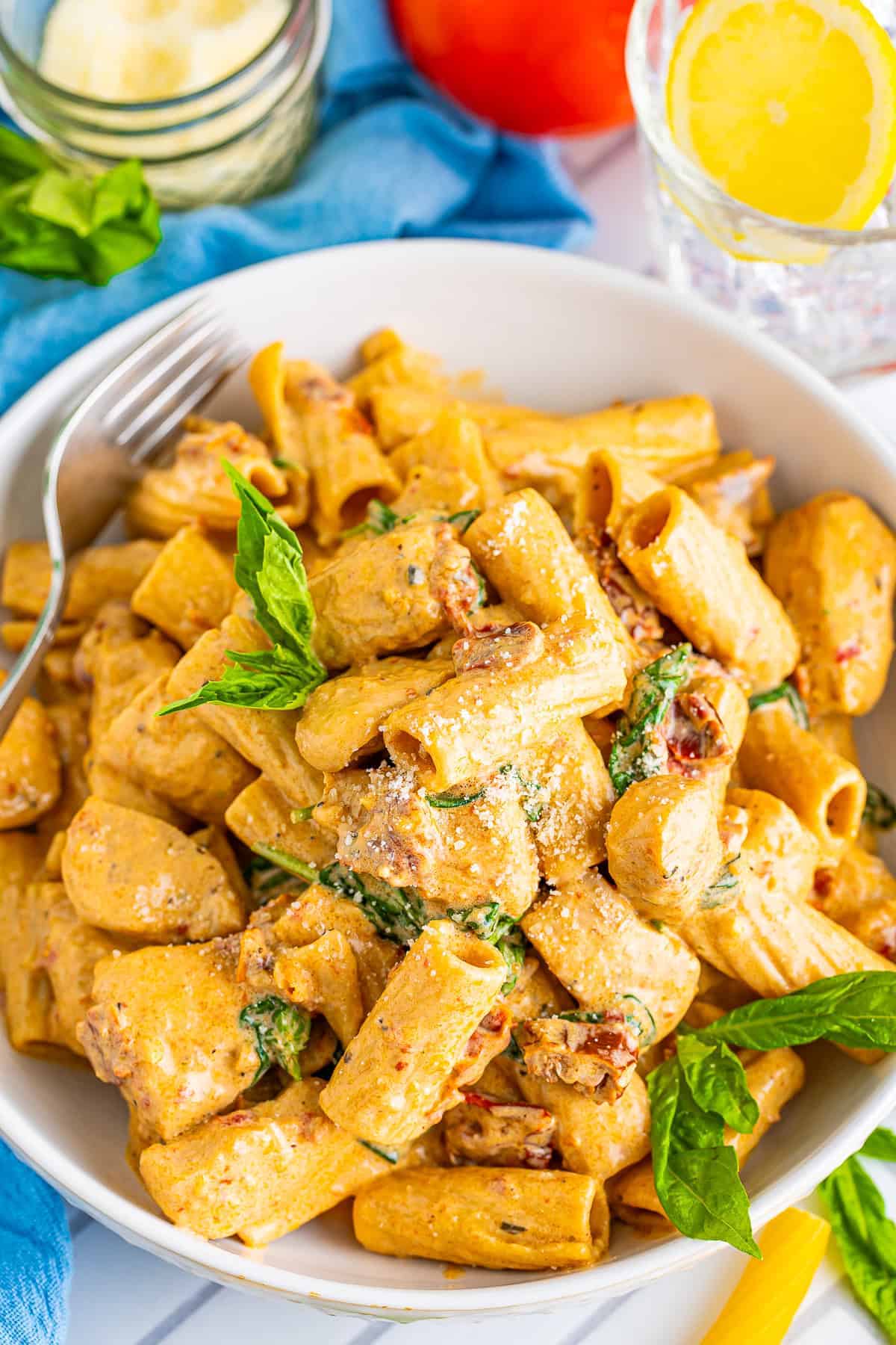 A bowl of creamy Tuscan chicken rigatoni topped with parmesan and fresh basil.