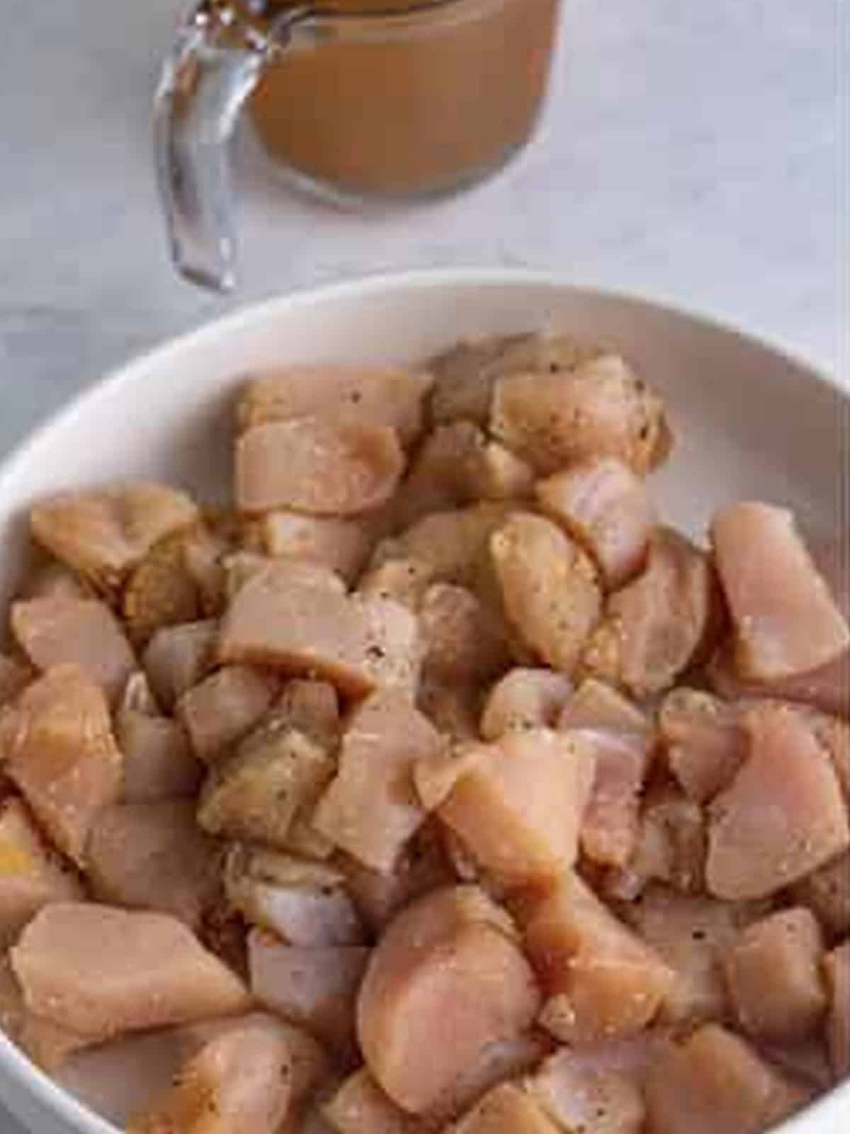Bite-sized chicken pieces seasoned in a pot.