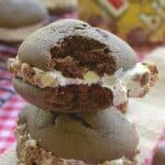 A stack of chocolate twix whoopie pies with marshmallow filling rolled in chopped Twix candy.