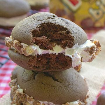 A stack of chocolate twix whoopie pies with marshmallow filling rolled in chopped Twix candy.