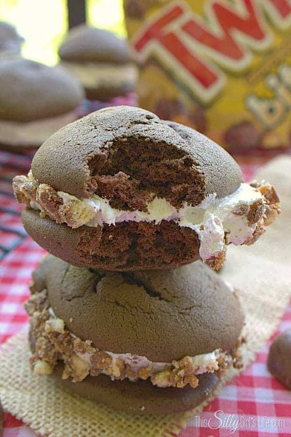A stack of chocolate twix whoopie pies with marshmallow filling rolled in chopped Twix candy.